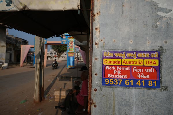 An advertising poster pasted on a shop at Dingucha village in Gandhinagar, India, Tuesday, Nov. 12, 2024. Poster reads in Gujarati "Make your dream of going abroad come true", on top and "Payment after visa". (AP Photo/Ajit Solanki)