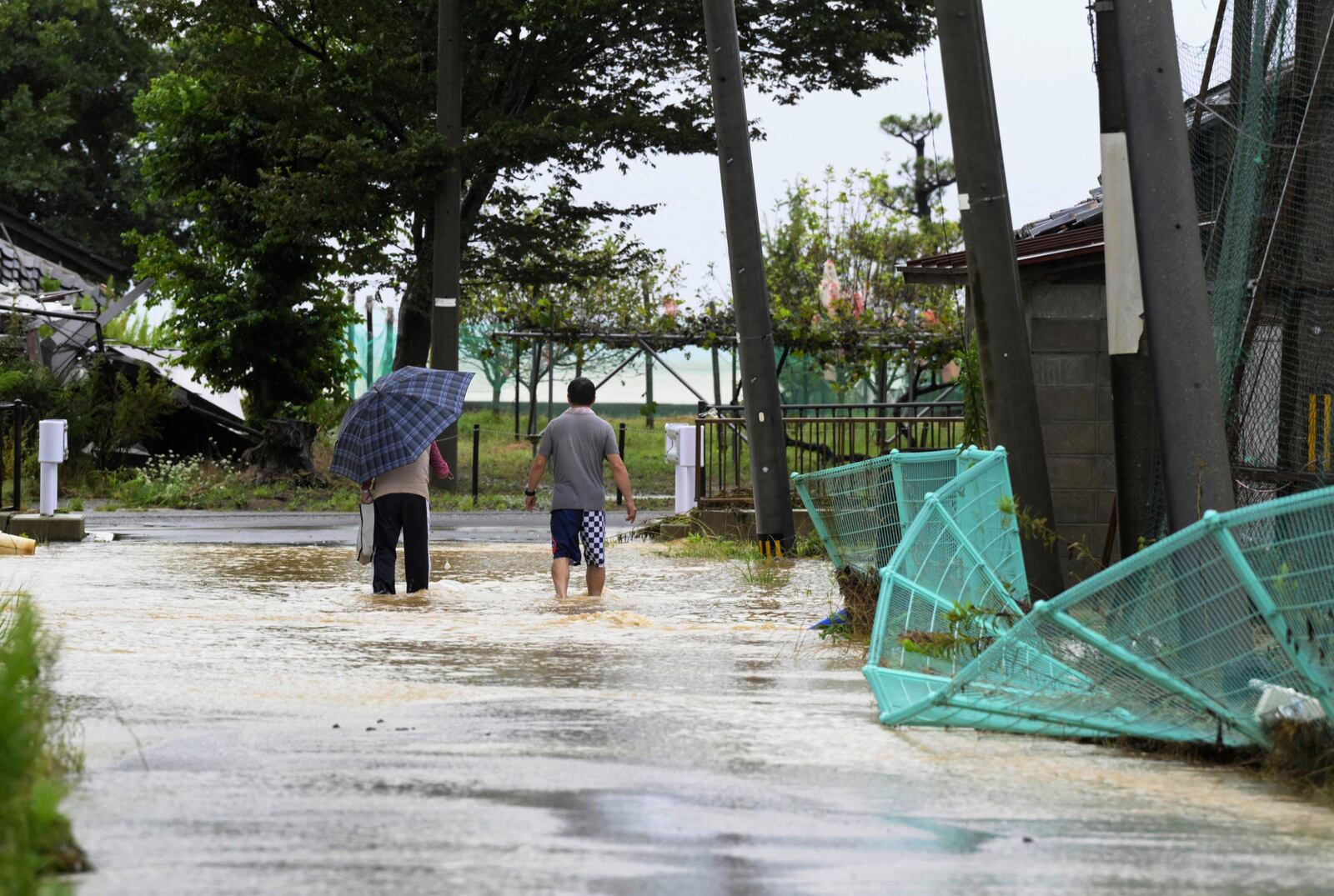 People wade through a partially flooded street in Suzu, Japan, Sunday, Sept. 22, 2024, following heavy rain in central Japan's Noto peninsula area, where a devastating earthquake took place on Jan. 1. (Kasumi Fukudome/Kyodo News via AP)