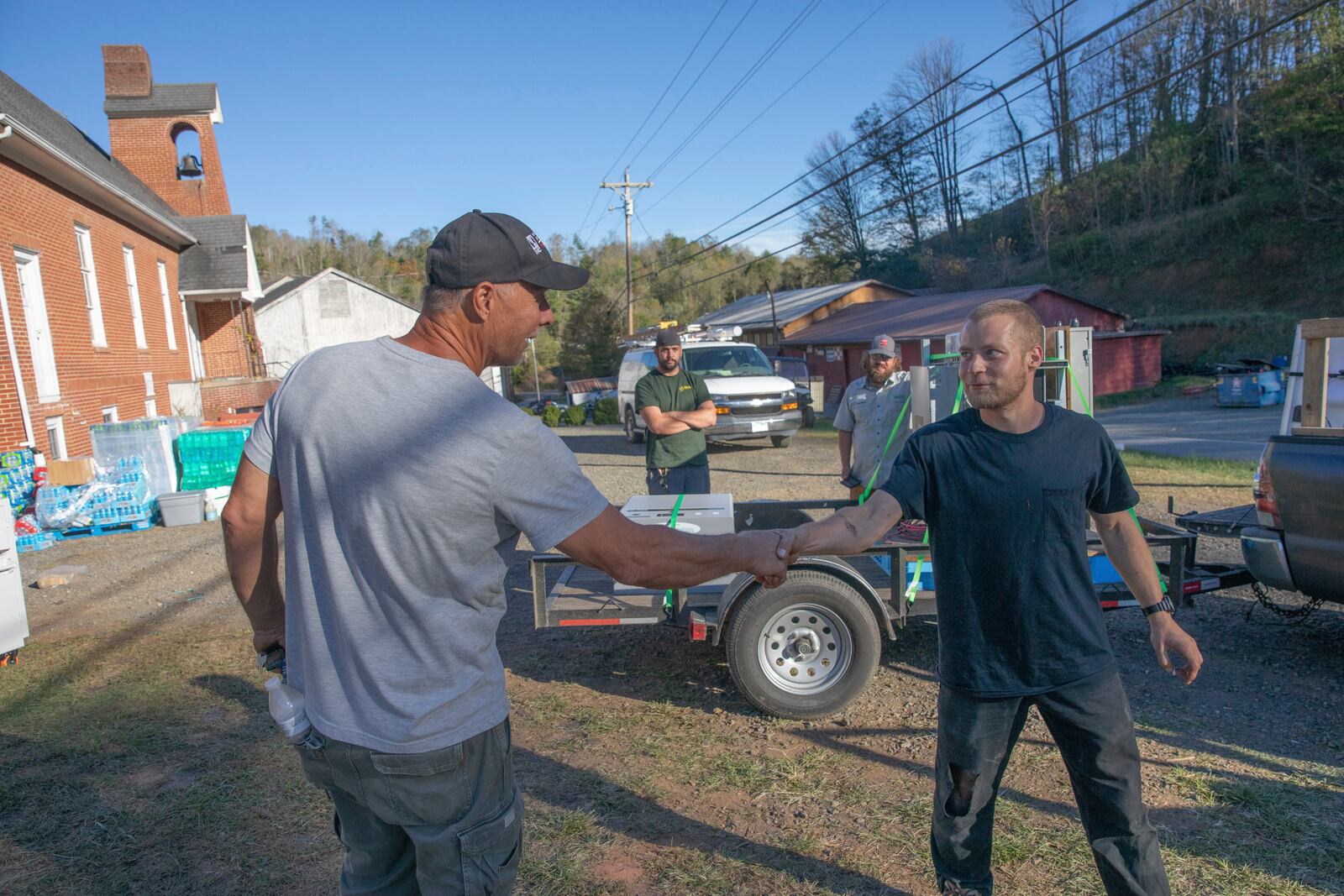 Bobby Renfro, left, thanks Footprint Project volunteer Henry Kovacs, right, after Kovacs helped install solar panels and a battery at a community building in Tipton Hill, N.C. on Oct. 9, 2024. (AP Photo/Gabriela Aoun Angueria)