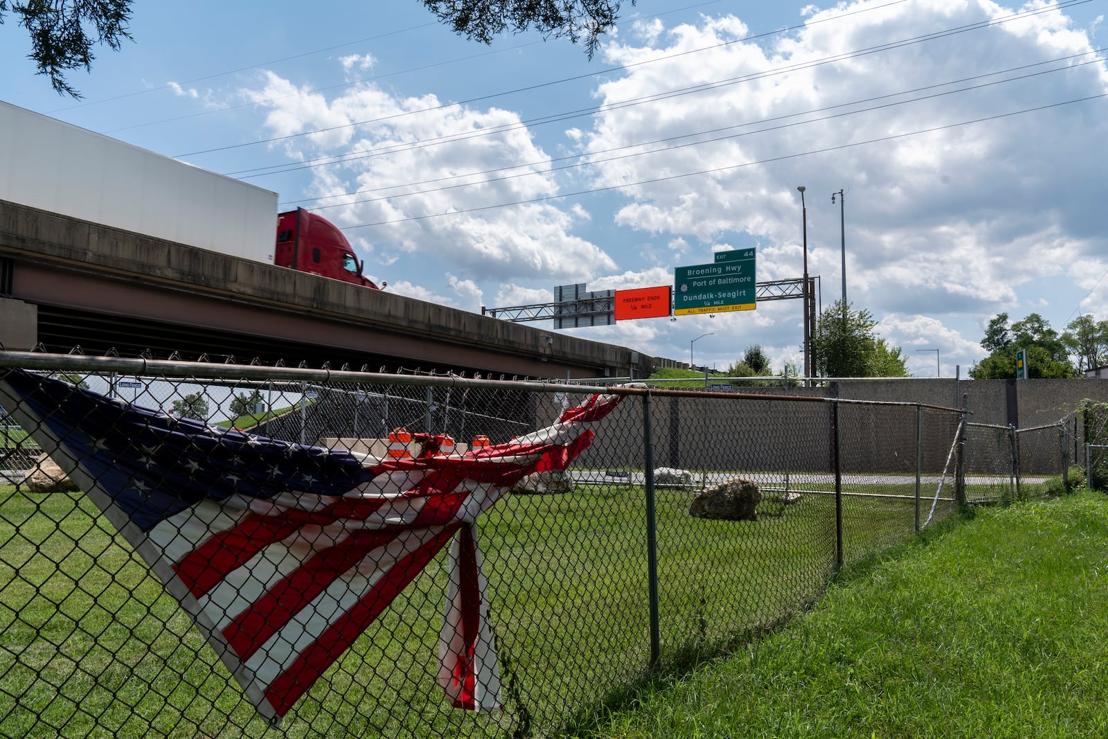 A semi truck drives past on the remaining portion of the Francis Scott Key Bridge, Tuesday, Aug. 13, 2024, as seen from the backyard of Linwood Jackon's home in Turner Station, Md. (AP Photo/Stephanie Scarbrough)