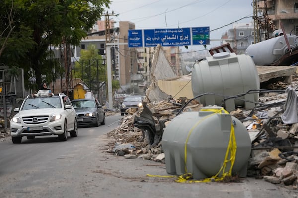 Displaced residents drive past the rubble of a destroyed building as they return to their villages, following a ceasefire between Israel and Hezbollah, Wednesday, Nov. 27, 2024, in Tyre, southern Lebanon. (AP Photo/Hussein Malla)