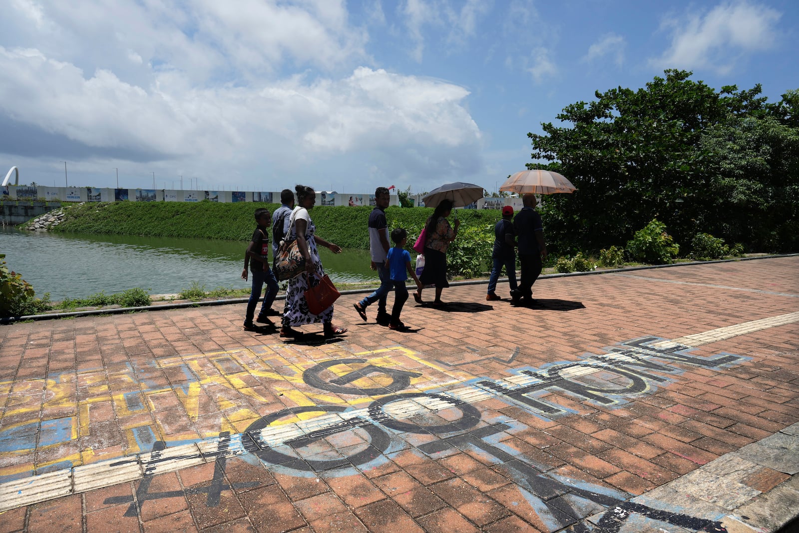 People walk past a graffiti near the 2022 protest site that reads "Go Home Gota," a slogan under which Sri Lankans where mobilized during the public uprising that led to the ousting of the then president Gotabaya Rajapaksa, in Colombo, Sri Lanka, Monday, Sept. 16, 2024. (AP Photo/Rajesh Kumar Singh)