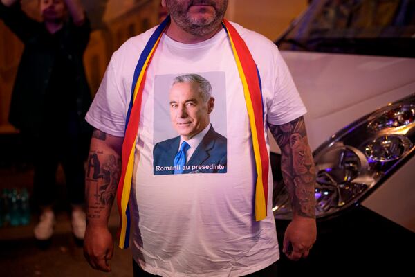 A man wears a t-shirt showing Calin Georgescu, winner of the first round of last year's voided election outside the headquarters of presidential candidate George Simion, after polls closed during the first round of the country's presidential election redo in Bucharest, Romania, Sunday, May 4, 2025. (AP Photo/Andreea Alexandru)