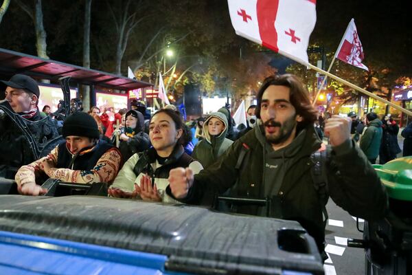 Protesters standing behind a barricade shout in a street during a rally against the results of the parliamentary elections amid allegations that the vote was rigged in Tbilisi, Georgia Tuesday, Nov. 19, 2024. (AP Photo/Zurab Tsertsvadze)