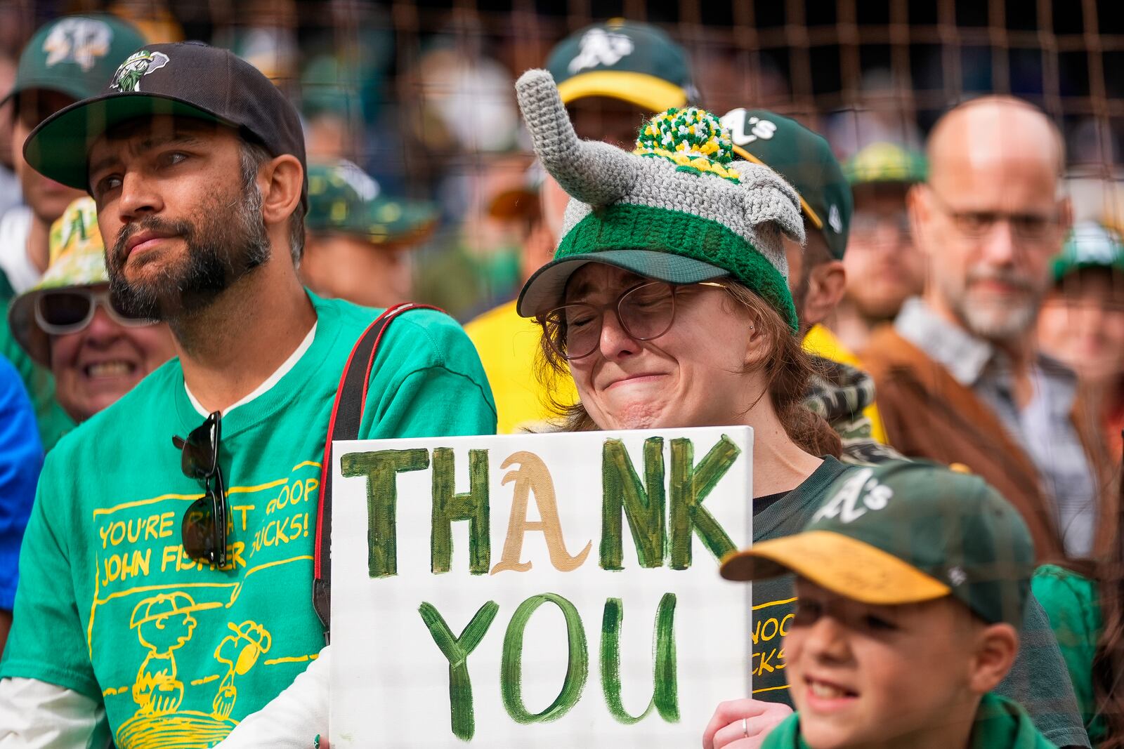 An Oakland Athletics fan cries while holding up a "thank you" sign towards the team's dugout following the Athletics' 6-4 loss to the Seattle Mariners in a baseball game, Sunday, Sept. 29, 2024, in Seattle. (AP Photo/Lindsey Wasson)