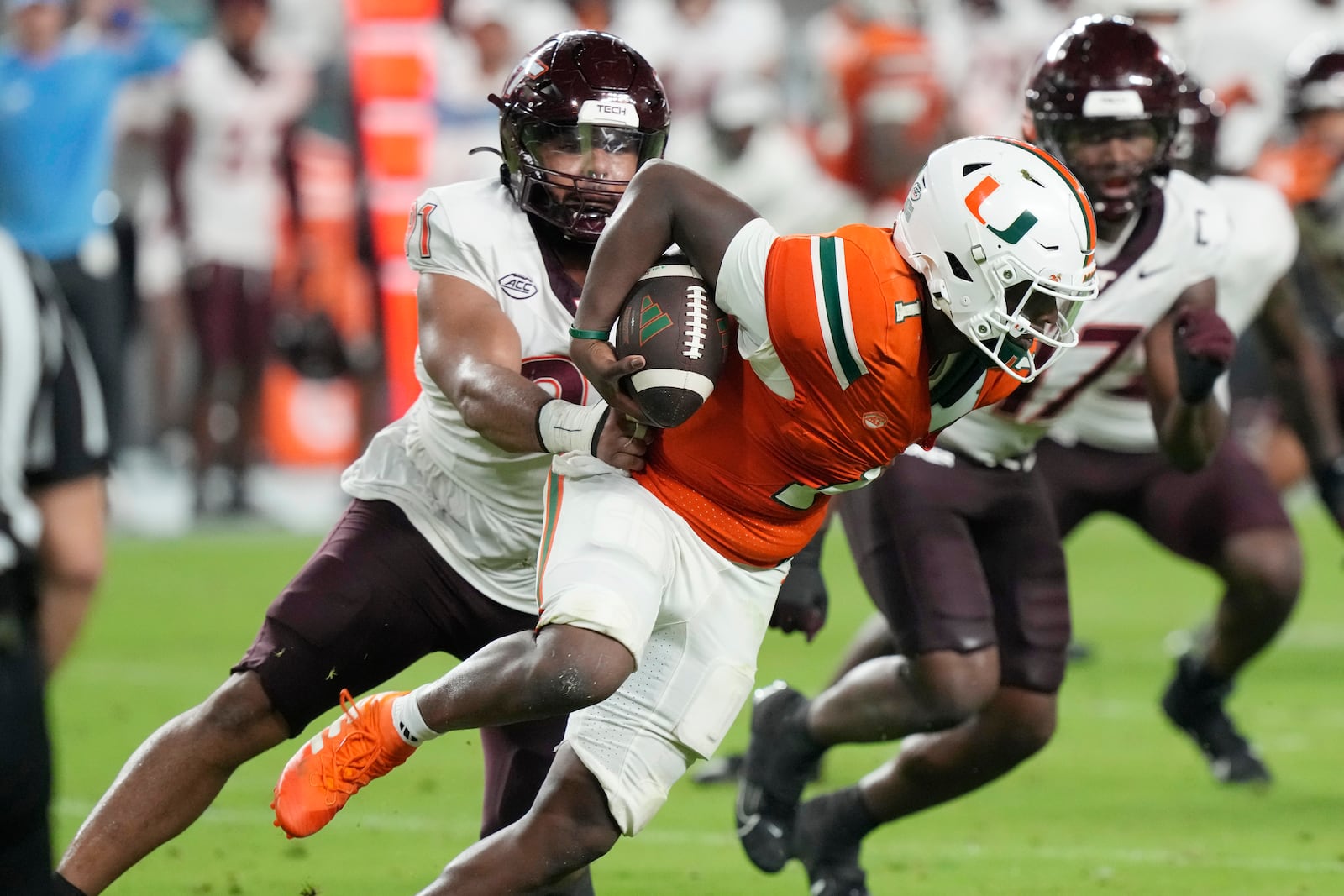 Virginia Tech defensive lineman Wilfried Pene (91) grabs Miami quarterback Cam Ward (1) during the first half of an NCAA college football game, Friday, Sept. 27, 2024, in Miami Gardens, Fla. (AP Photo/Marta Lavandier)