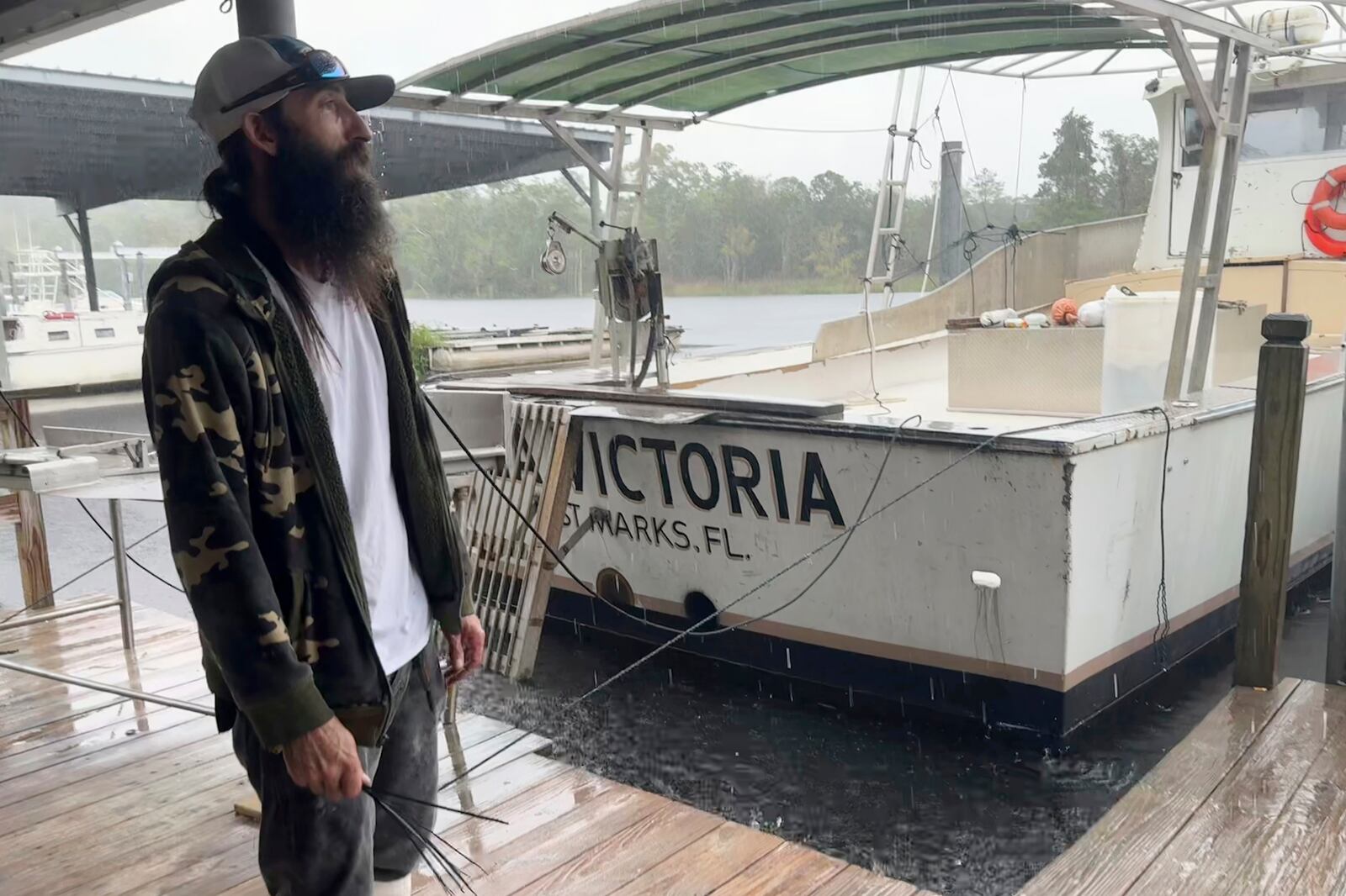 Darren Archer works on tying down a cover over a boat named the Susan D. docked in St. Marks, Fla. on Thursday Sept. 26, 2024. Archer, who works for the St. Marks Seafood company, plans to ride out Hurricane Helene on a boat. (AP Photo/Kate Payne)