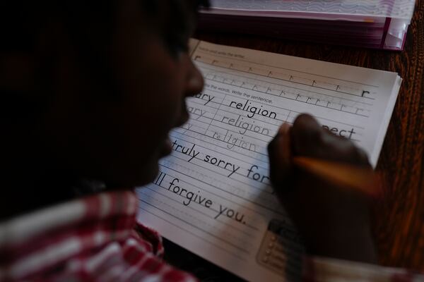 Gianna Young, 7, works on her letters with the word "religion" during homeschool lessons in the dining room of her Sunbury, Ohio, home on Tuesday, Nov. 12, 2024. (AP Photo/Carolyn Kaster)