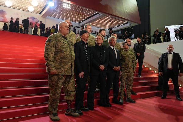 The Edge, from second left, Bono and Sean Penn pose with military personnel for photographers upon arrival at the premiere of the film 'Bono: Stories of Surrender' at the 78th international film festival, Cannes, southern France, Friday, May 16, 2025. (AP Photo/Natacha Pisarenko)