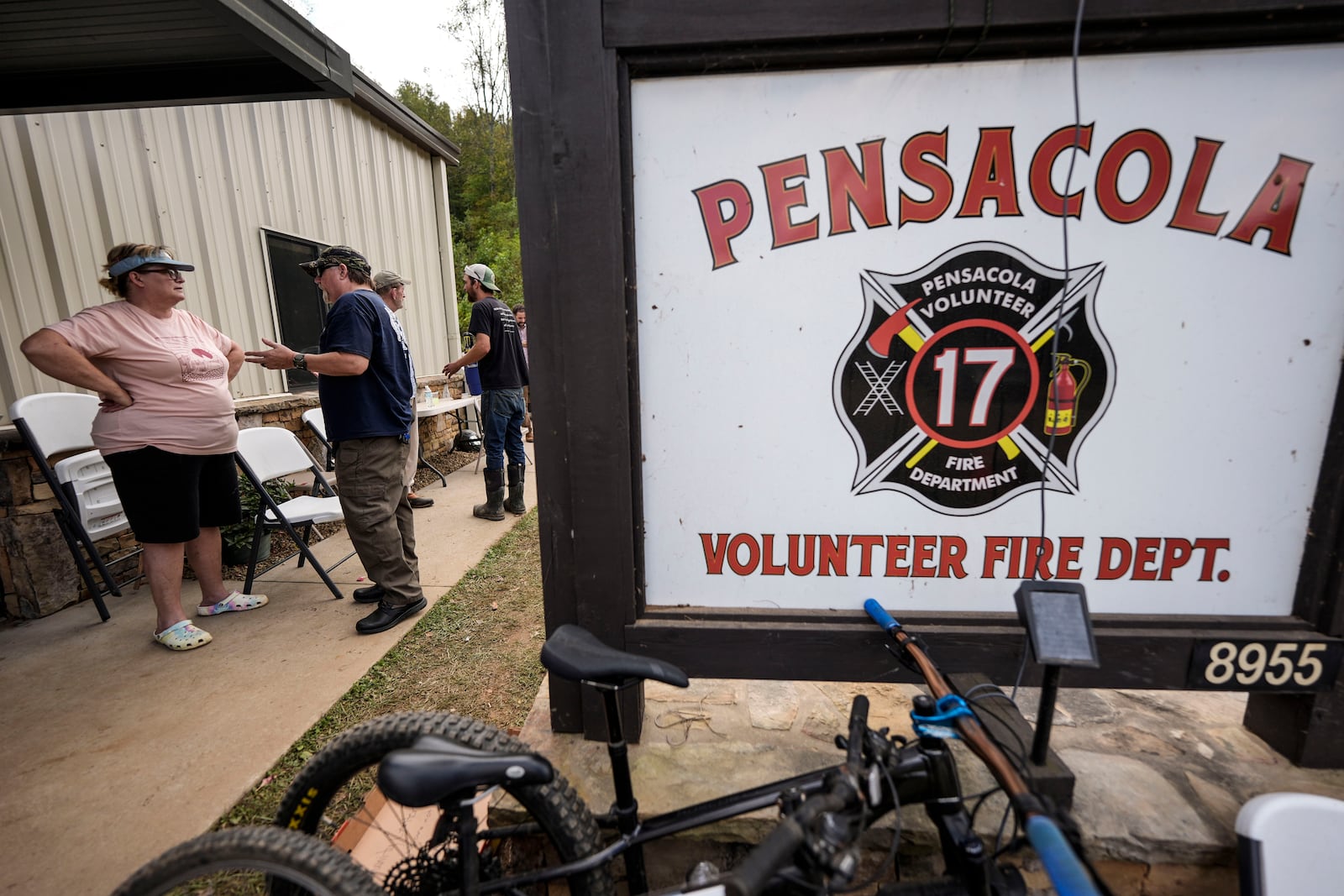 People speak outside the volunteer fire house in the aftermath of Hurricane Helene, Thursday, Oct. 3, 2024, in Pensacola, N.C. (AP Photo/Mike Stewart)