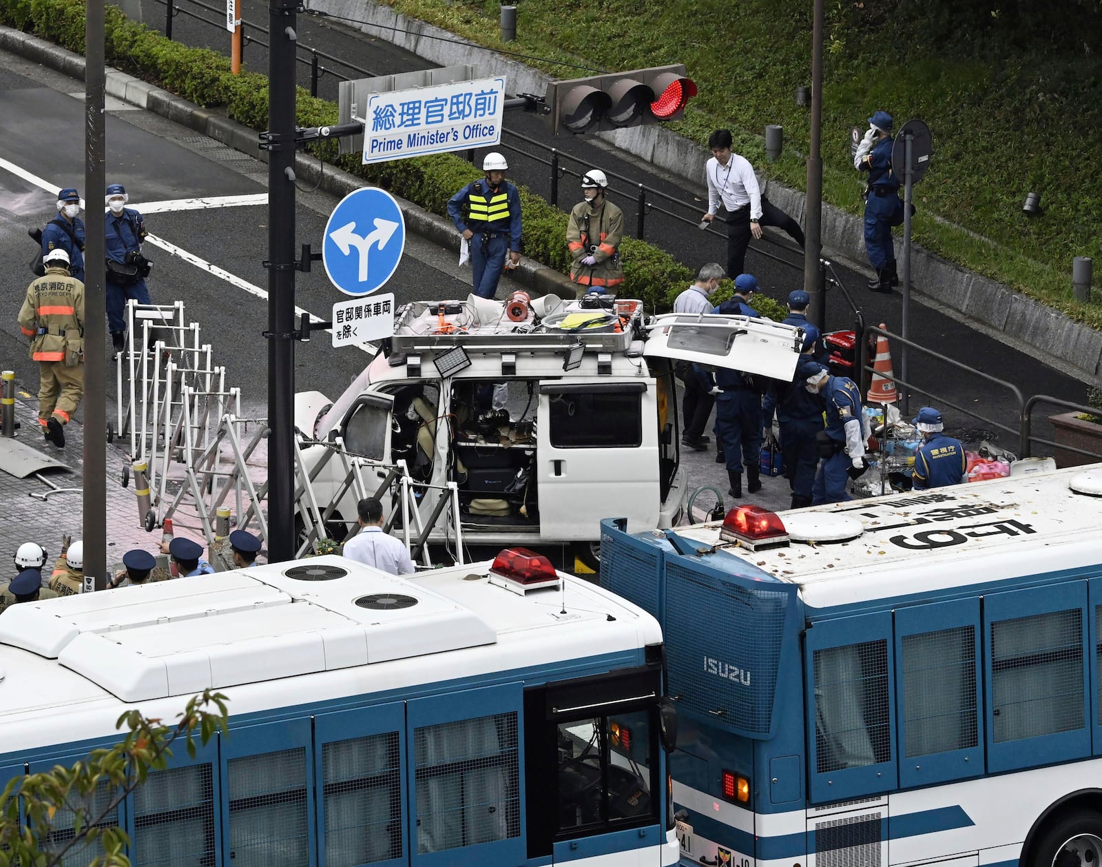 Officials work near a vehicle, center, which was stuck against a barricade near the prime minister's office in Tokyo Saturday, Oct. 19, 2024. (Kyodo News via AP)