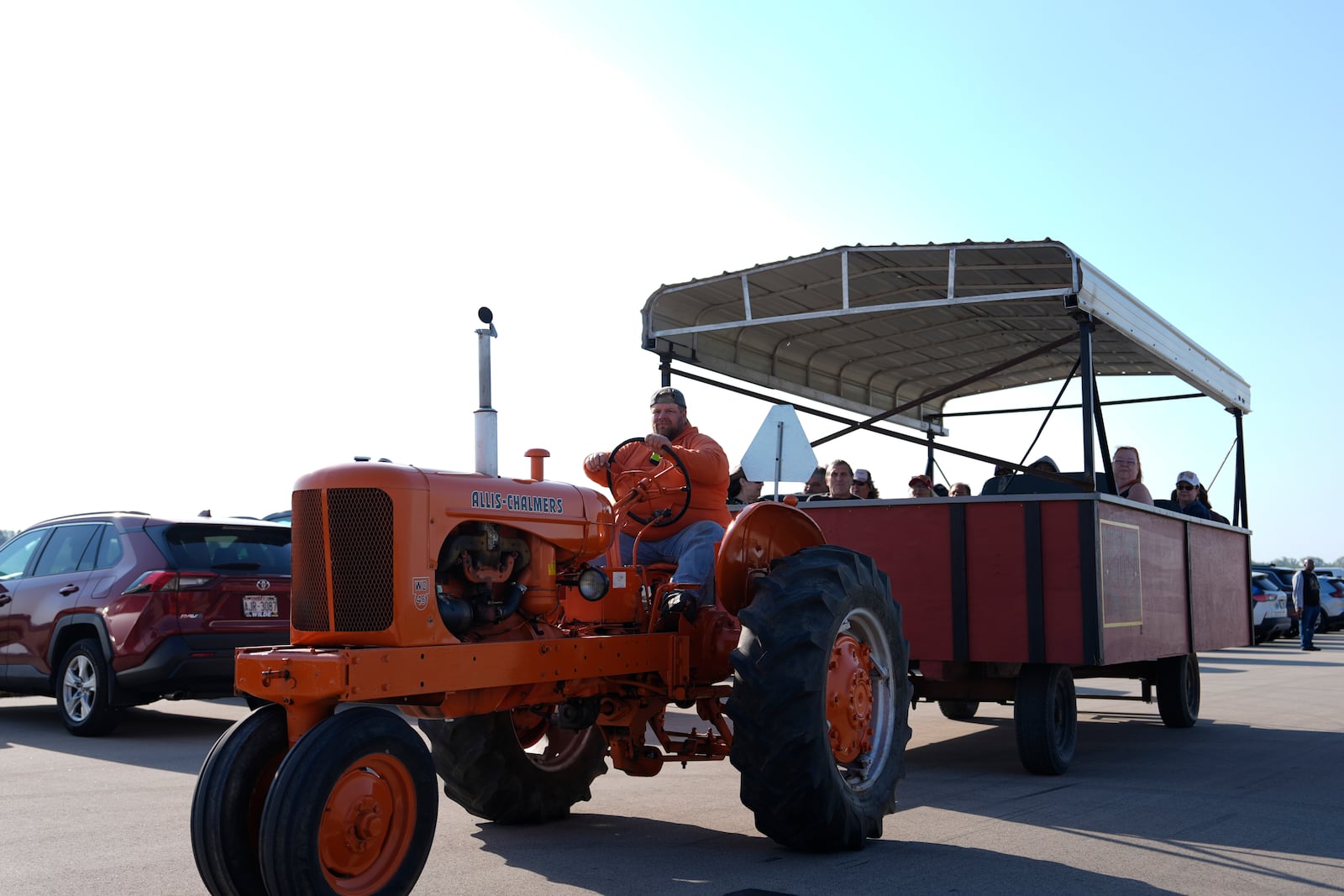 A tractor pulling a wagon drives attendees in the parking lot to the entrance of a campaign rally for Republican presidential nominee former President Donald Trump at Dodge County Airport, Sunday, Oct. 6, 2024, in Juneau, Wis. (AP Photo/Julia Demaree Nikhinson)