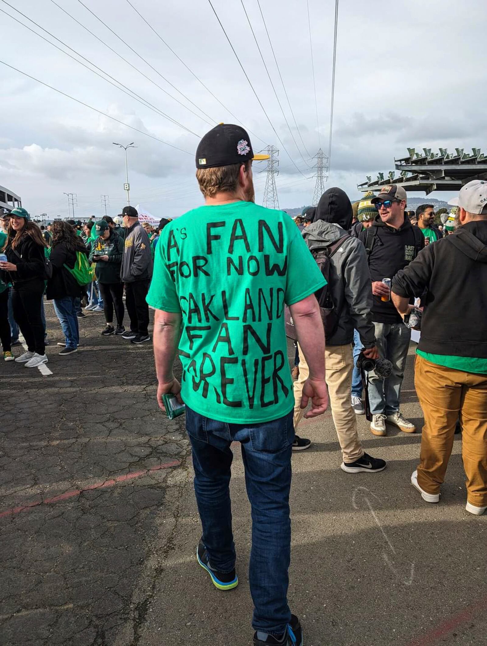 A fan wearing a shirt expressing his dismay with the A's move from Oakland while walking through the Oakland Coliseum parking lot on Opening Night, March 28, 2024, in Oakland, Calif. (AP Photo/Michael Liedtke)