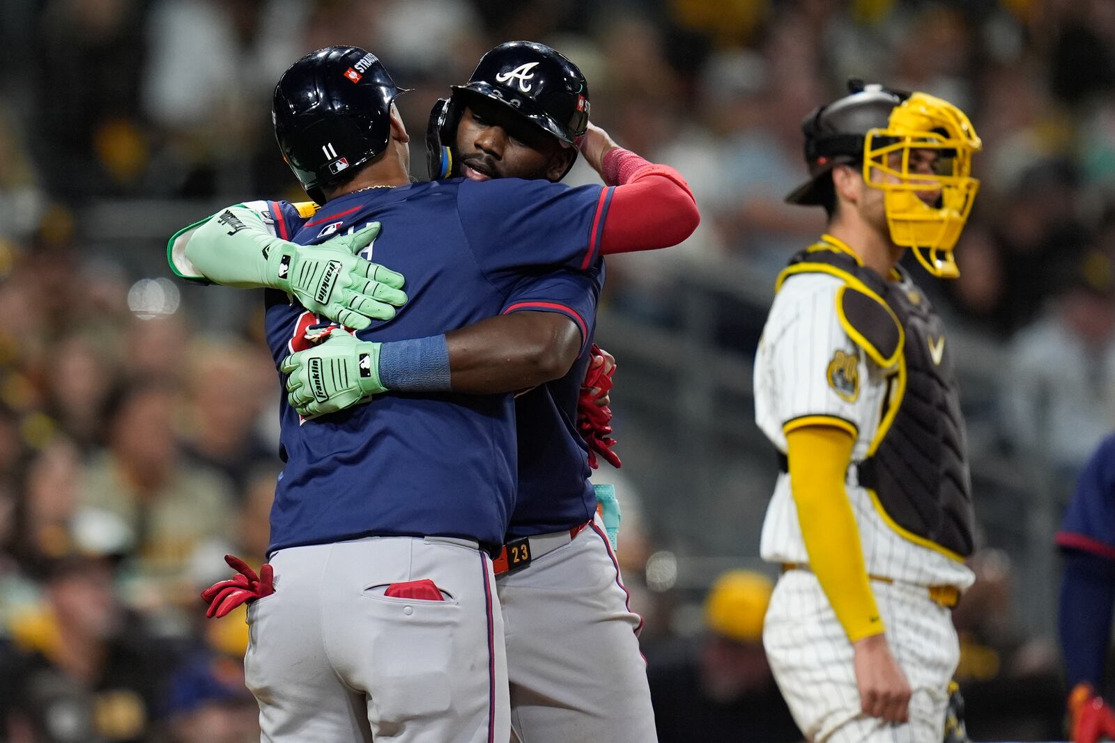 Atlanta Braves' Michael Harris II, center, hugs Orlando Arcia, left, after Harris' two-run home run during the eighth inning in Game 2 of an NL Wild Card Series baseball game against the San Diego Padres, Wednesday, Oct. 2, 2024, in San Diego. (AP Photo/Gregory Bull)