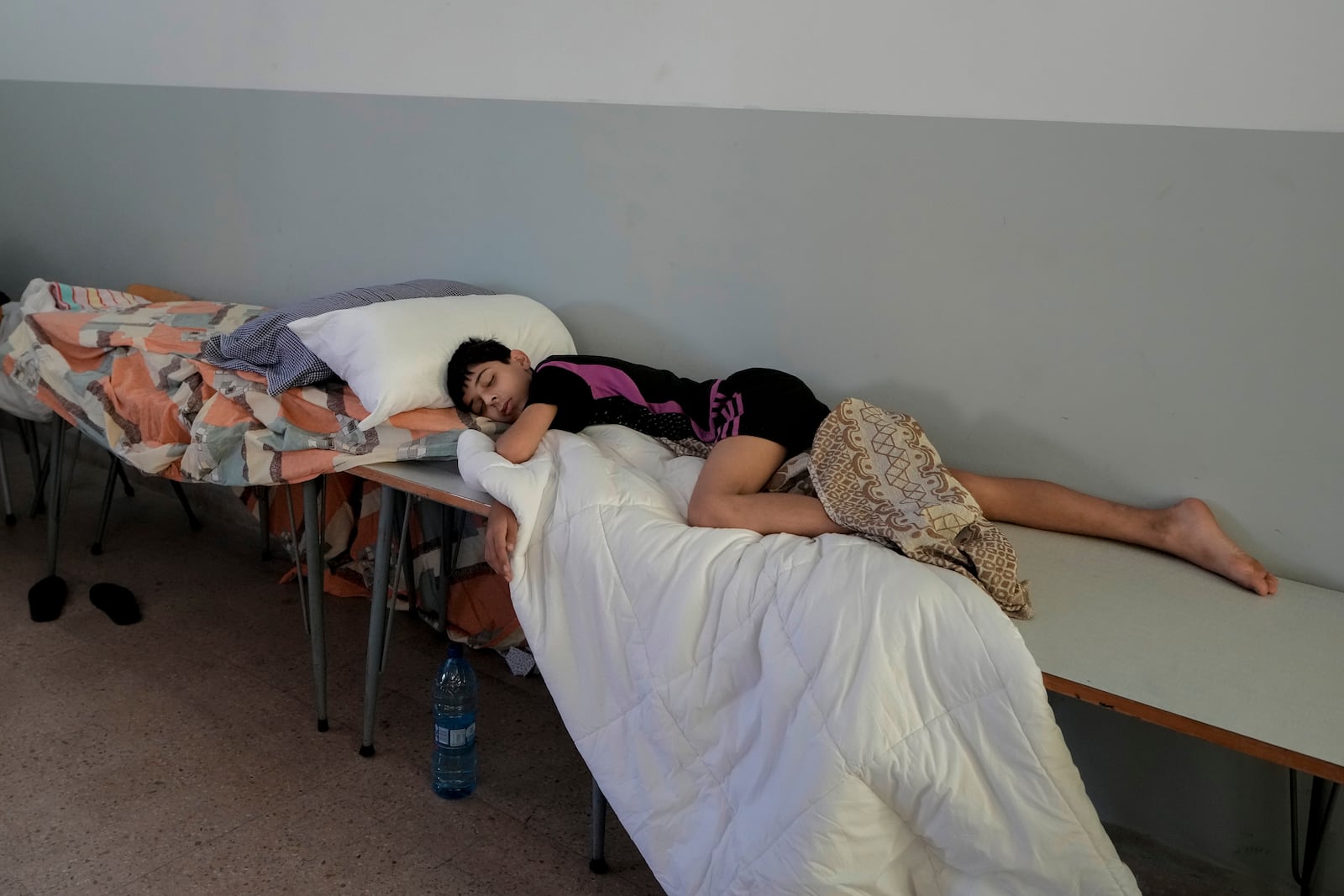 A displaced boy sleeps in a classroom in Beirut, after fleeing the Israeli airstrikes in the south with his family, Thursday, Sept. 26, 2024. (AP Photo/Bilal Hussein)