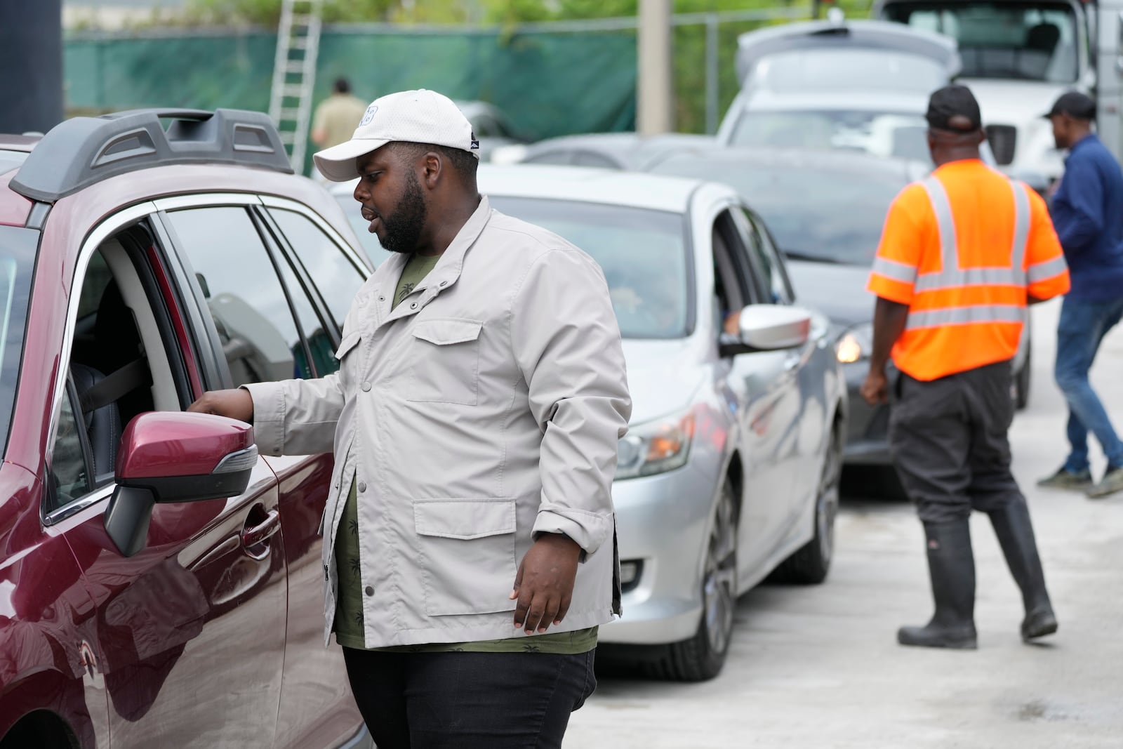 North Miami Beach, Fla., commissioner McKenzie Fleurimond, left, checks cars as residents line up to receive sandbags from the city to help prevent flooding, as Hurricane Milton prepares to strike Florida, Tuesday, Oct. 8, 2024, in North Miami Beach. (AP Photo/Wilfredo Lee)