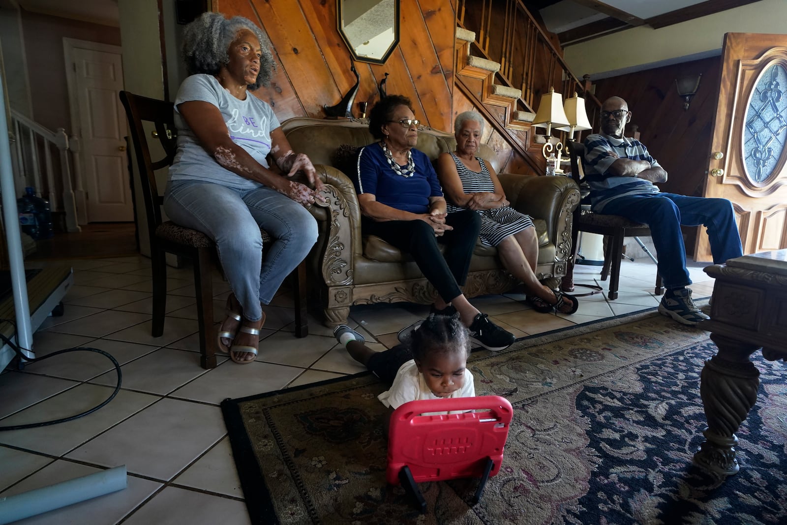 FILE - Kole Jones, great grandson of Lydia Gerard, left, a member of Concerned Citizens of St. John the Baptist Parish, plays with a toy as she and fellow residents speak to reporters in Reserve, La., near the Denka Performance Elastomer Plant on Sept. 15, 2022.(AP Photo/Gerald Herbert)