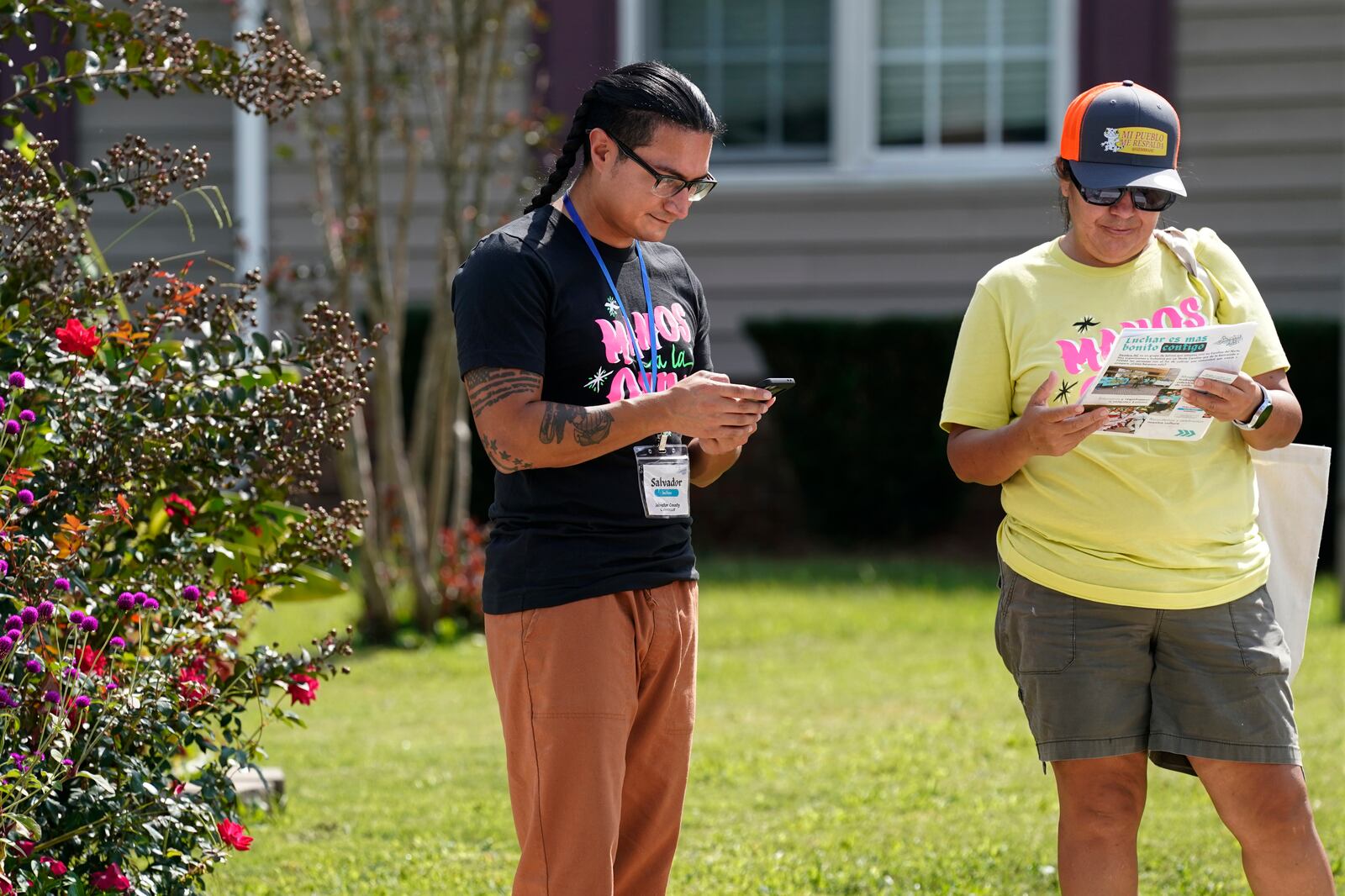 Salvador Fonseca, left, and Elena Jimenez take notes after visiting a home during a voter engagement event for the Latino community in Greensboro, N.C., Saturday, Sept. 21, 2024. (AP Photo/Chuck Burton)