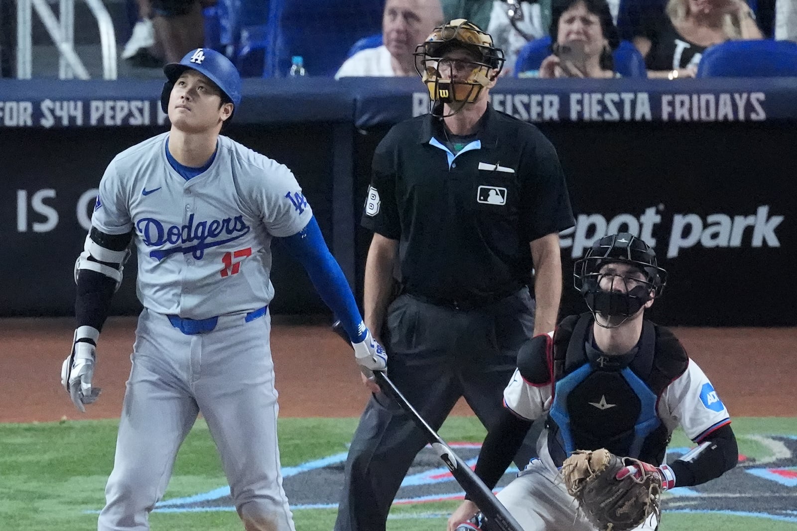 Los Angeles Dodgers' Shohei Ohtani, left, of Japan, watches the ball as he hits a home run, scoring Max Muncy and Chris Taylor, during the ninth inning of a baseball game against the Miami Marlins, Thursday, Sept. 19, 2024, in Miami. (AP Photo/Wilfredo Lee)