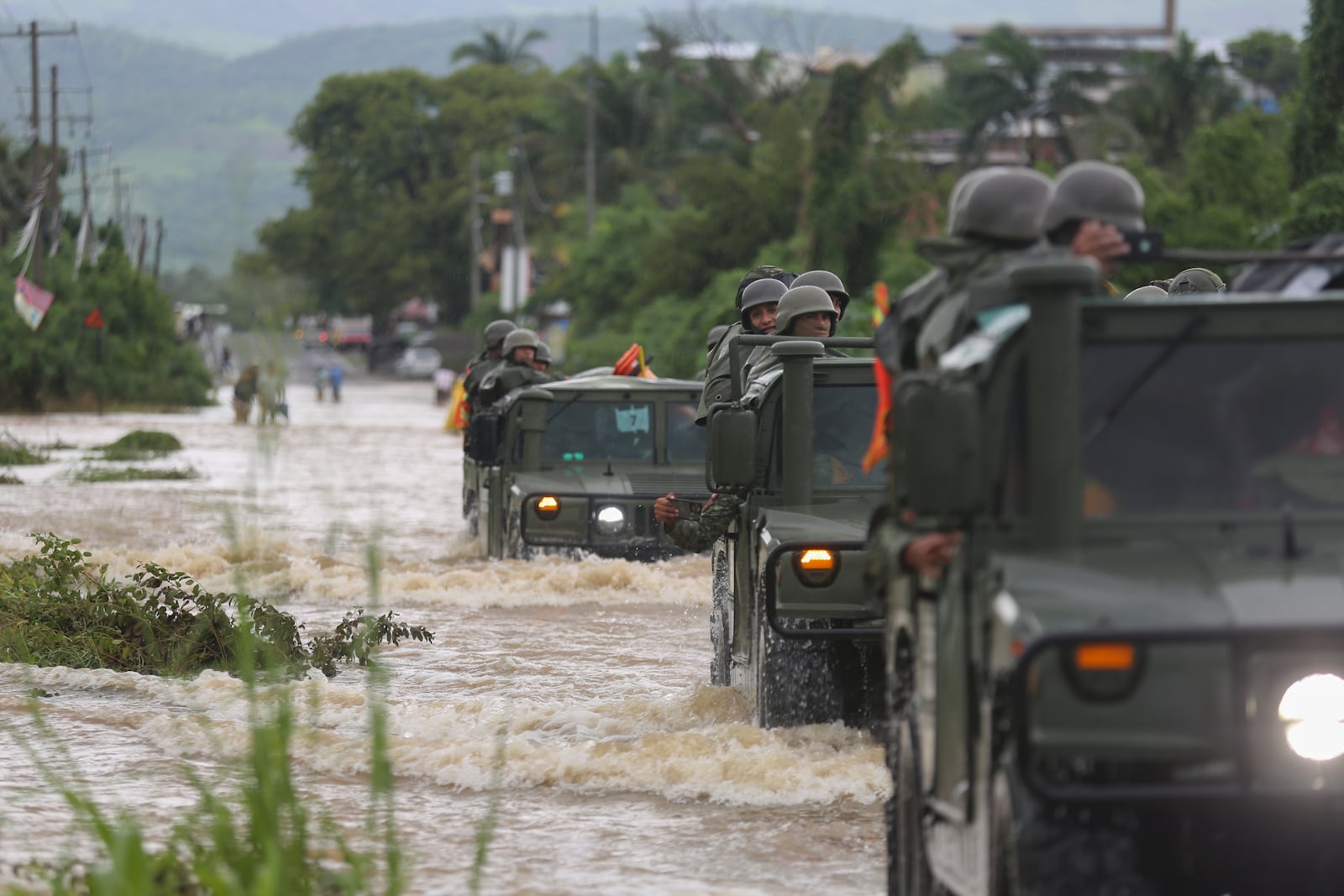 A caravan of Army vehicles make their way through a street flooded by the passing of Hurricane John, in Acapulco, Mexico, Friday, Sept. 27, 2024. (AP Photo/Bernardino Hernandez)