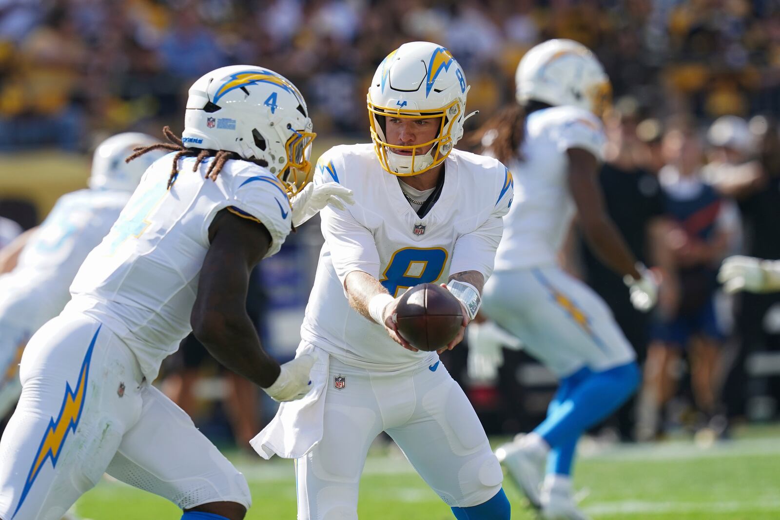 Los Angeles Chargers quarterback Taylor Heinicke (8) hands the ball off to running back Gus Edwards, left, during the second half of an NFL football game against the Pittsburgh Steelers, Sunday, Sept. 22, 2024, in Pittsburgh. (AP Photo/Matt Freed)