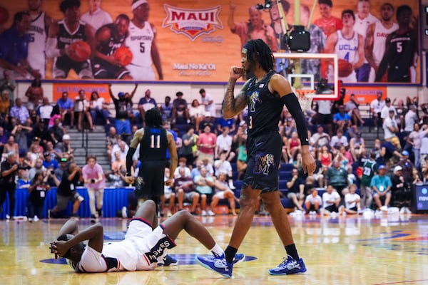 Memphis guard Colby Rogers, right, celebrates a 99-97 win in overtime as UConn guard Hassan Diarra, left, lies on the ground in an NCAA college basketball game at the Maui Invitational Monday, Nov. 25, 2024, in Lahaina, Hawaii. (AP Photo/Lindsey Wasson)