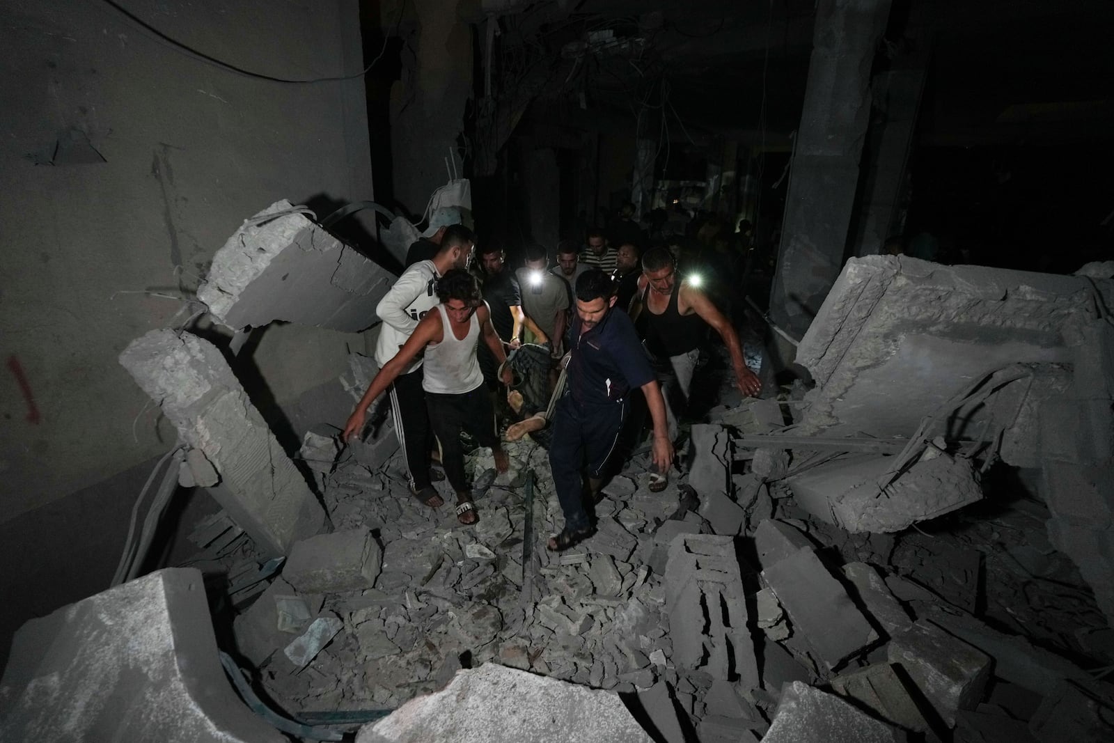 Palestinians carry the body of a person who was found under the rubble of a destroyed mosque following an Israeli airstrike in Deir al-Balah, Sunday, Oct. 6, 2024. (AP Photo/Abdel Kareem Hana)