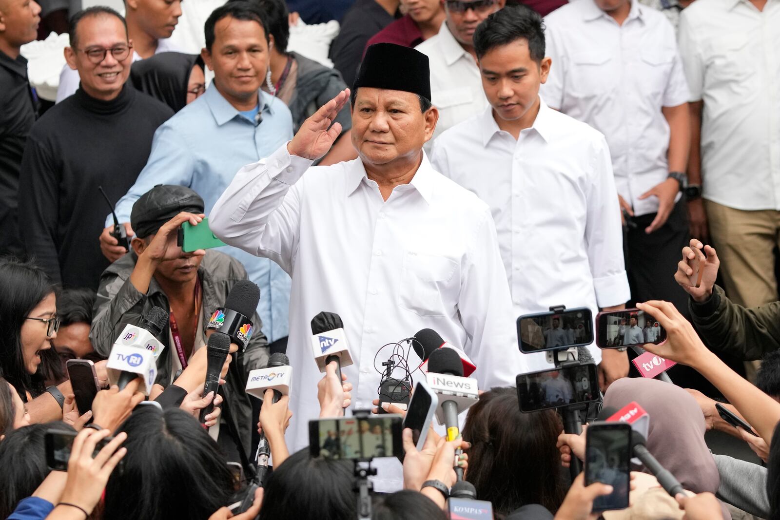 FILE - Indonesian Defense Minister and president-elect Prabowo Subianto, center, salutes to journalists in front of his running mate Gibran Rakabuming Raka, rear center, the eldest son of Indonesian President Joko Widodo, during their formal declaration as president and vice president-elect at the General Election Commission building in Jakarta, Indonesia, Wednesday, April 24, 2024. (AP Photo/Achmad Ibrahim, File)