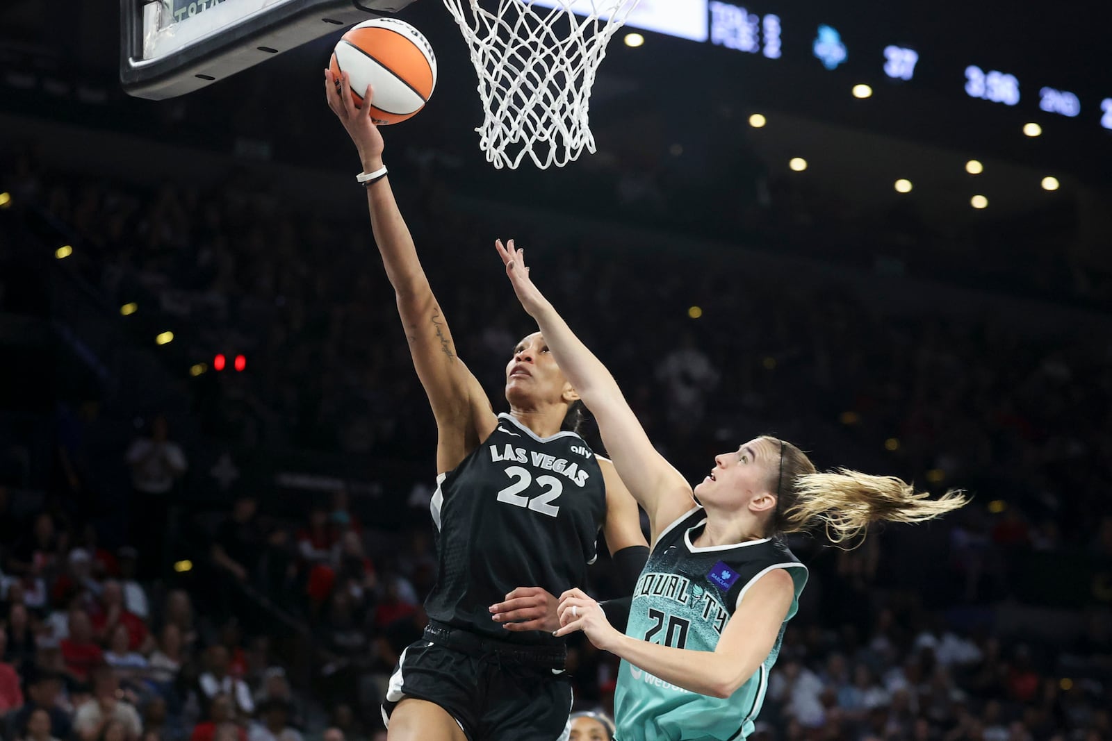 Las Vegas Aces center A'ja Wilson (22) goes up for a basket over New York Liberty guard Sabrina Ionescu (20) during the first half of a WNBA Semifinal game, Sunday, Oct. 6, 2024, in Las Vegas. (AP Photo/Ian Maule)