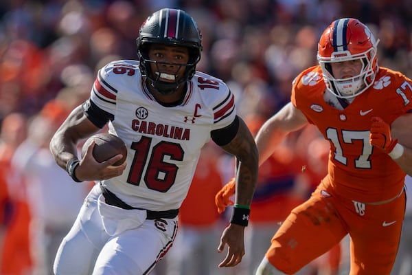 South Carolina quarterback LaNorris Sellers (16) runs with the ball while pursued by Clemson linebacker Wade Woodaz (17) in the first half of an NCAA college football game Saturday, Nov. 30, 2024, in Clemson, S.C. (AP Photo/Jacob Kupferman)