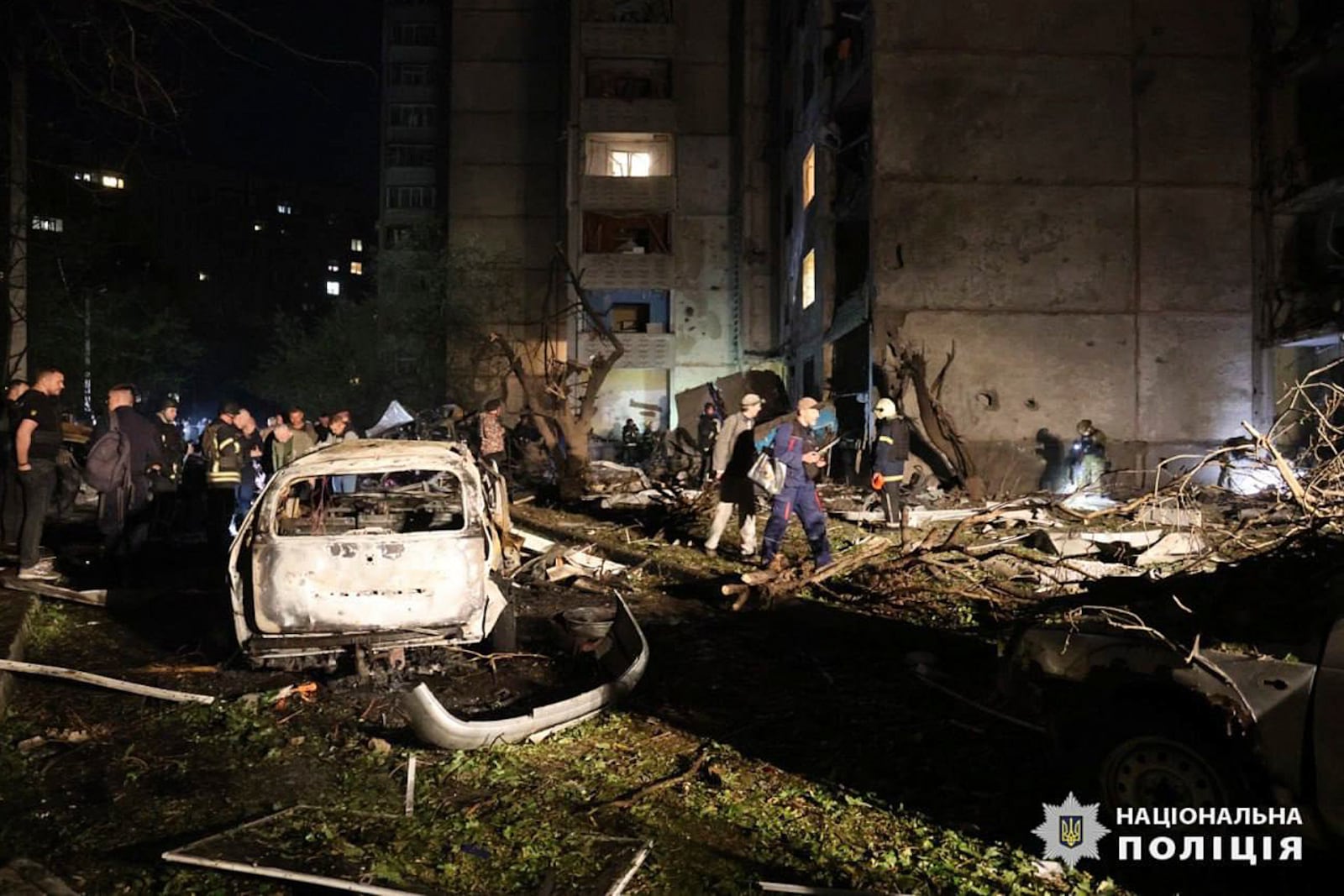 People mill around damaged cars and debris after a Russian strike on a residential building in Kharkiv, Ukraine early Sunday Sept. 22, 2024. (Ukrainian National Police via AP)