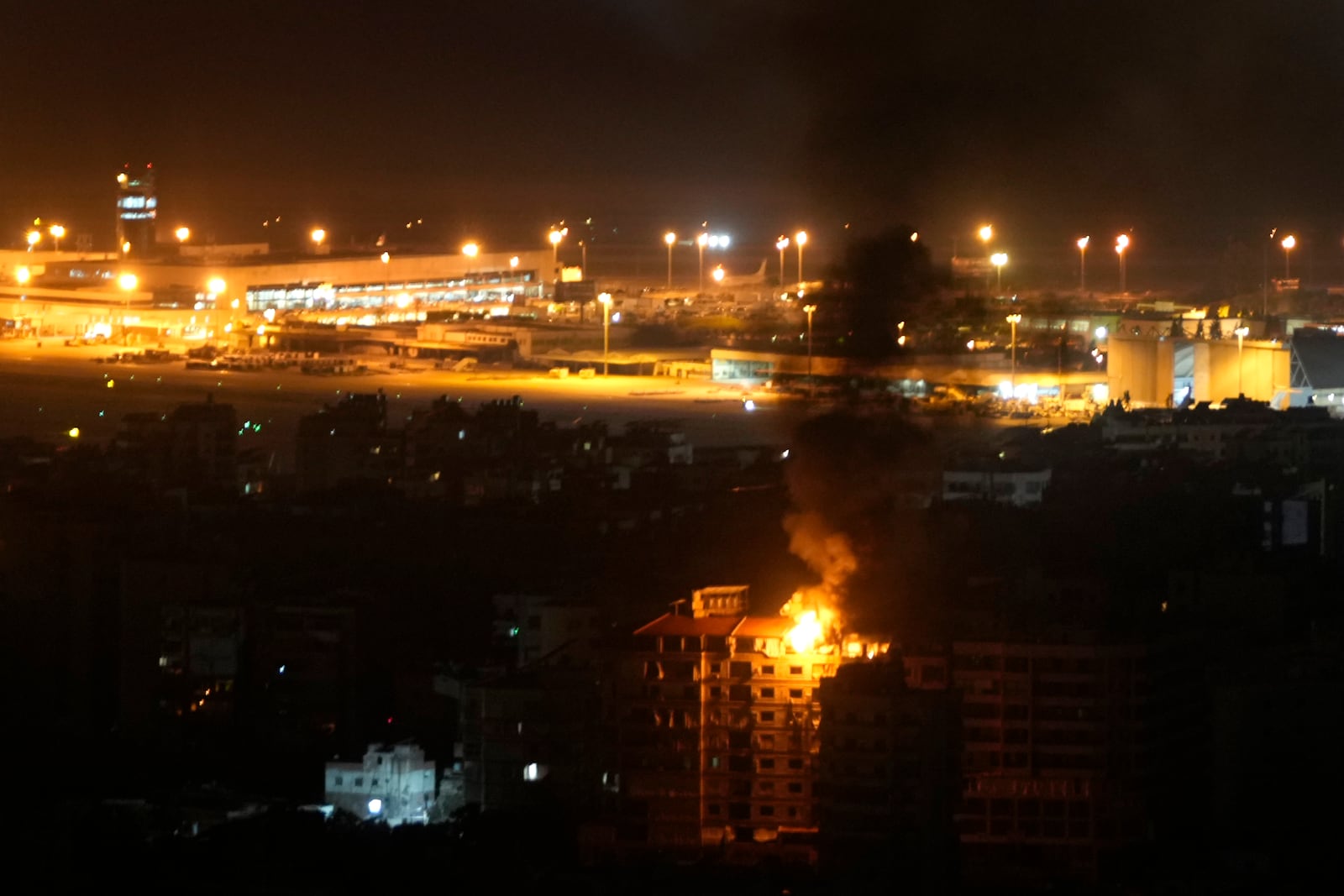 Flames and smoke rise from a building that was hit by an Israeli airstrike in Dahiyeh, as Rafik Hariri International airport is seen in the background, in Beirut, Lebanon, Friday, Oct. 4, 2024. (AP Photo/Hussein Malla)