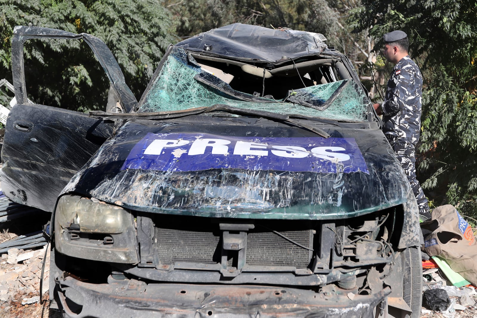 A policeman checks a destroyed vehicle, at the site where an Israeli airstrike hit a compound housing journalists, killing three media staffers from two different news agencies according to Lebanon's state-run National News Agency, in Hasbaya village, southeast Lebanon, Friday, Oct. 25, 2024. (AP Photo/Mohammed Zaatari)