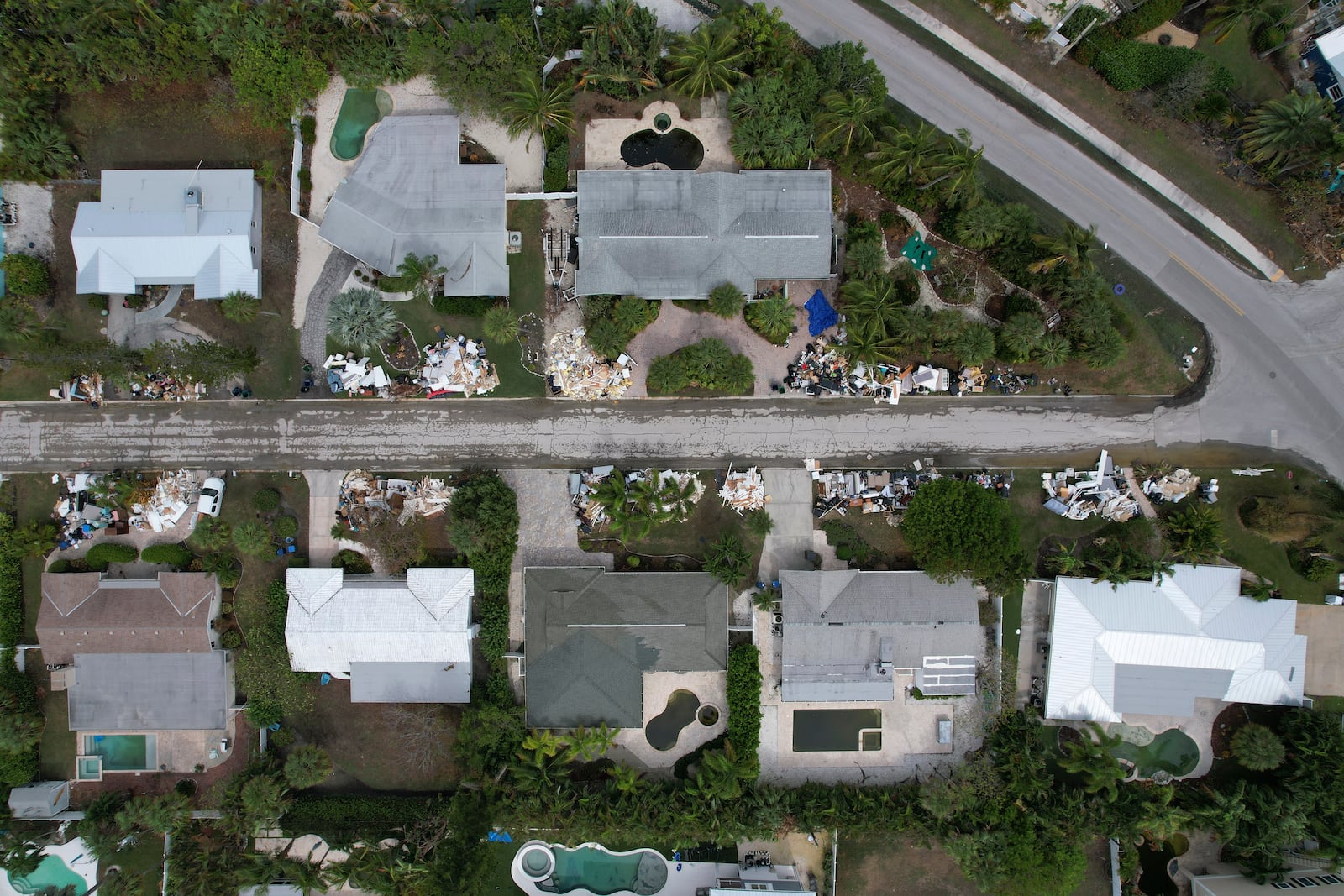 In this image taken with a drone, piles of furniture and household items destroyed in Hurricane Helene flooding sit piled up outside of homes ahead of the arrival of Hurricane Milton, Tuesday, Oct. 8, 2024, in Holmes Beach on Anna Maria Island, Fla. (AP Photo/Rebecca Blackwell)