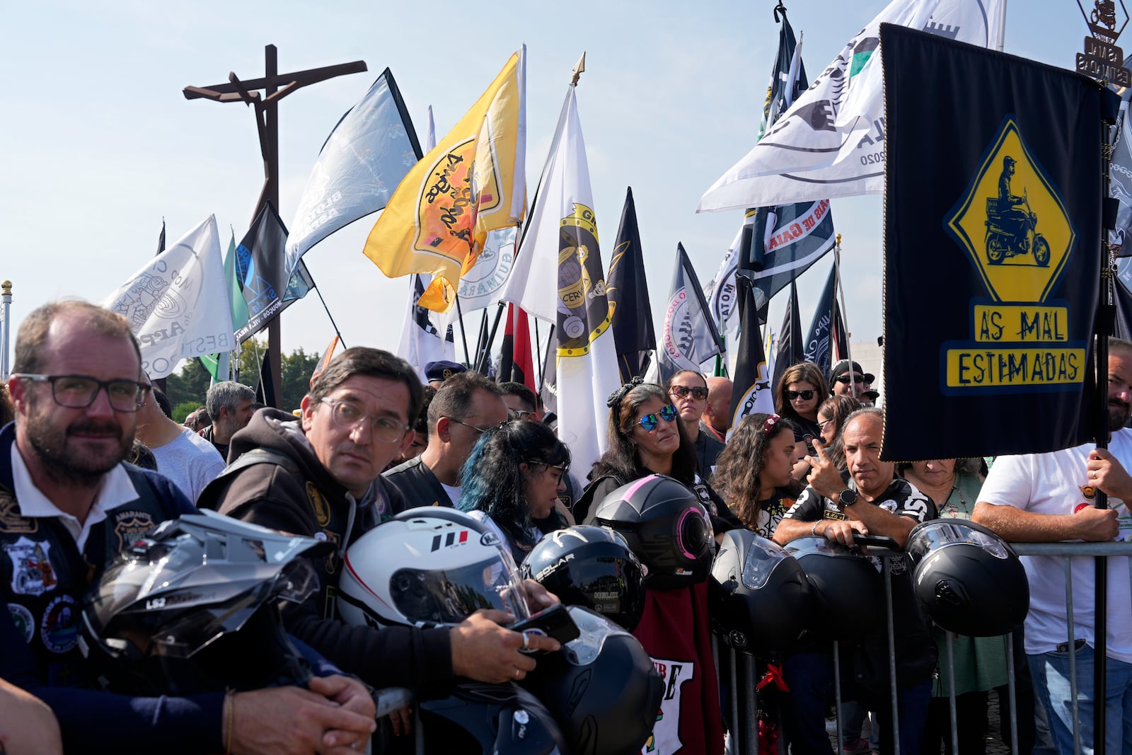 Motorcyclists holding their helmets and their groups' banners gather at the Roman Catholic holy shrine of Fatima to attend the IX Pilgrimage of the Blessing of Helmets that draws tens of thousands, in Fatima, Portugal, Sunday, Sept. 22, 2024. (AP Photo/Ana Brigida)