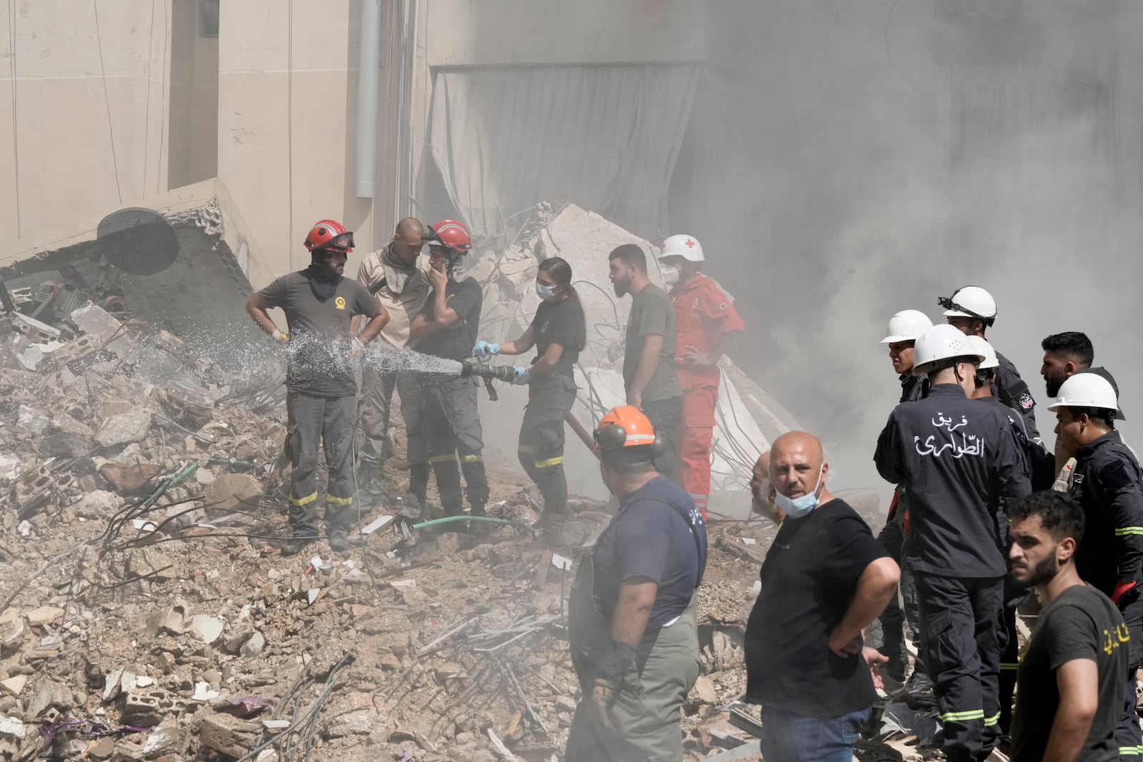 Civil defense workers extinguish a fire as smoke rises from the site of Friday's Israeli strike in Beirut's southern suburbs, Saturday, Sept. 21, 2024. (AP Photo/Bilal Hussein)