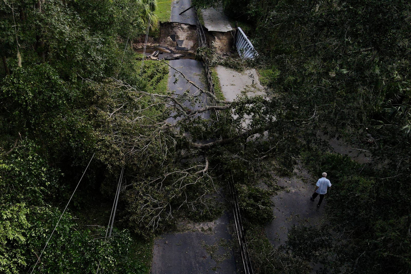 Del Ockey, a seasonal Florida resident from Canada, walks near the damaged bridge that leads onto his property during Hurricane Milton, Friday, Oct. 11, 2024, in Riverview, Fla. (AP Photo/Julio Cortez)