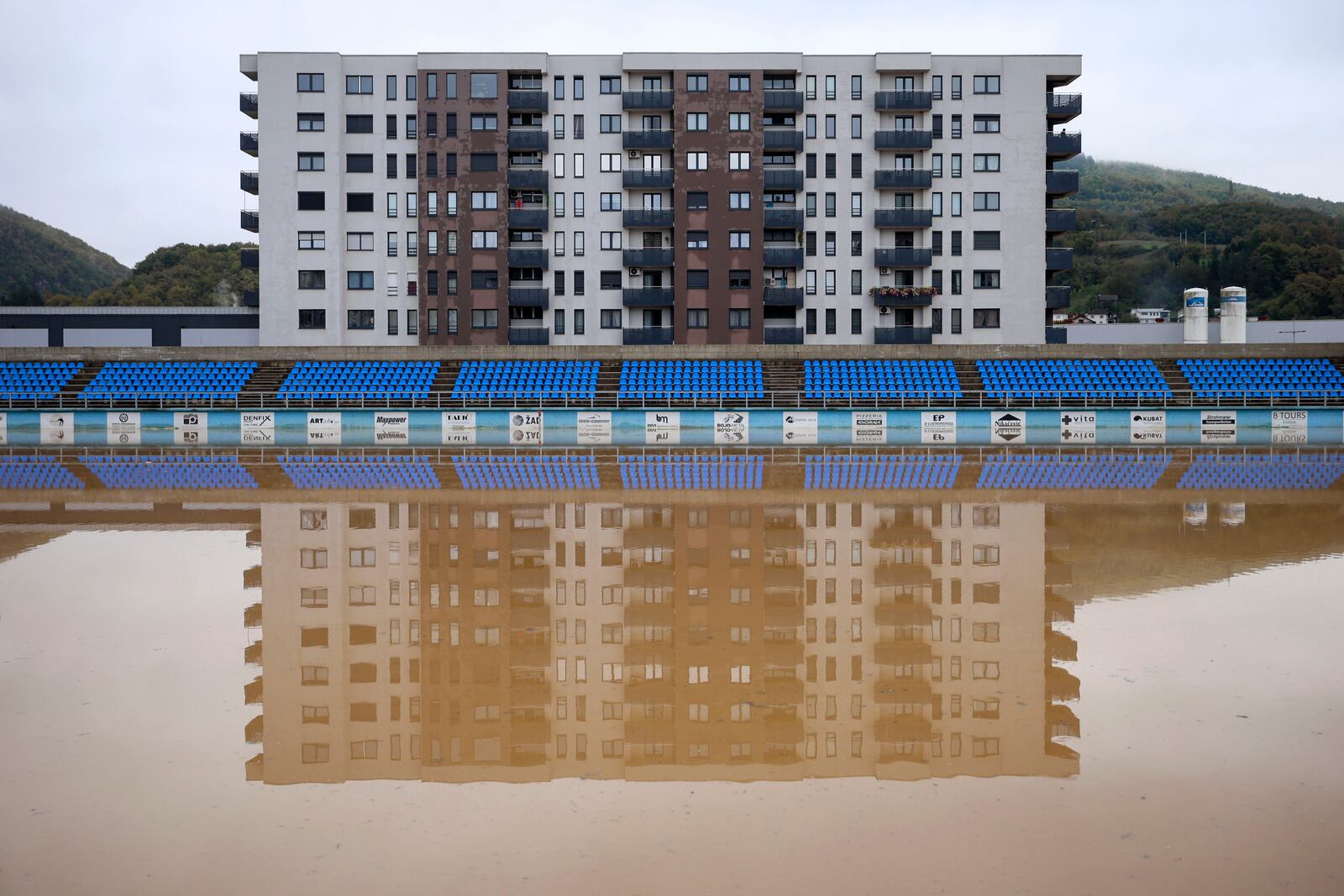 Apartment buildings are reflected at a flooded soccer field after a heavy rain in the village of Kiseljak, northern Bosnia, Friday, Oct. 4, 2024. (AP Photo/Armin Durgut)