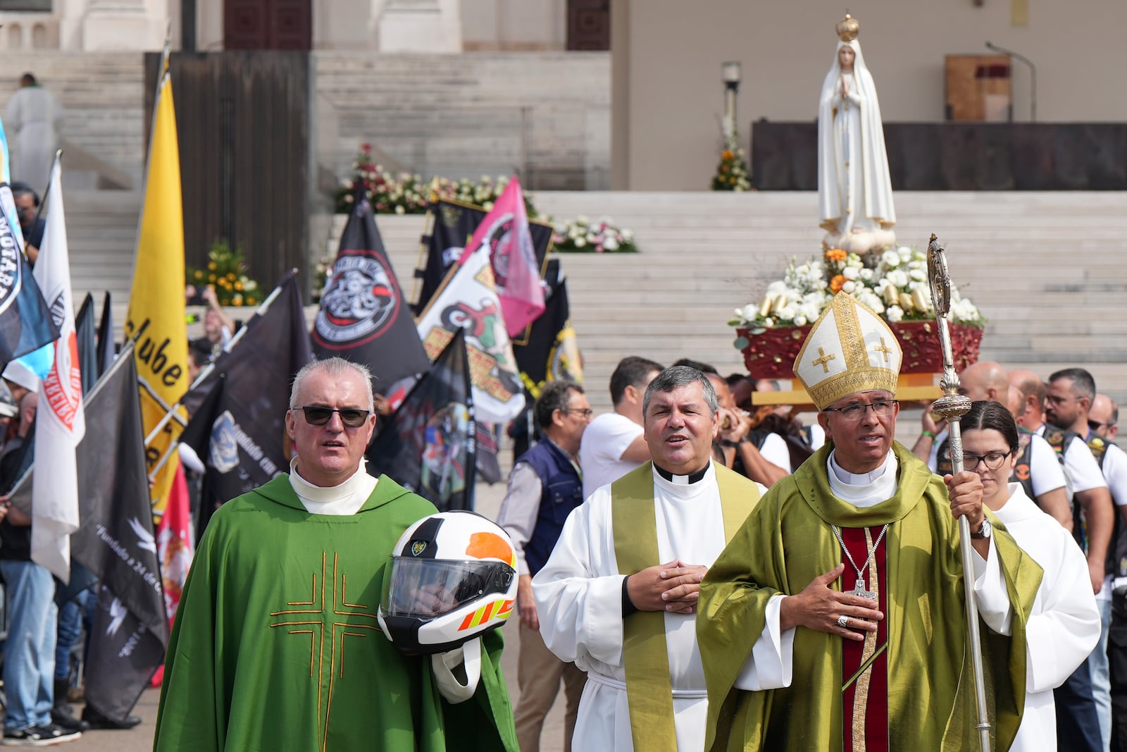 A priest carrying a Portuguese National Republican Guard motorcyclist helmet walks ahead of the Our Lady of Fatima statue in a procession closing the IX Pilgrimage of the Blessing of Helmets at the Roman Catholic holy shrine of Fatima to attend, in Fatima, Portugal, Sunday, Sept. 22, 2024. (AP Photo/Ana Brigida)