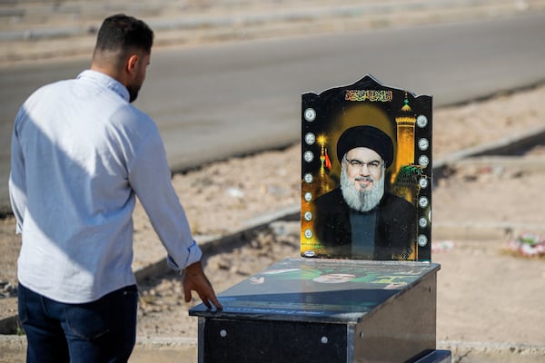 A Iraqi Shiite man prays by a symbolic grave set up for the former leader of Lebanon's Hezbollah militant group, Sayyed Hassan Nasrallah, who was killed by an Israeli airstrike in Beirut, at Wadi al-Salam cemetery near Najaf, Iraq, Tuesday, Nov. 19, 2024. (AP Photo/Anmar Khalil)