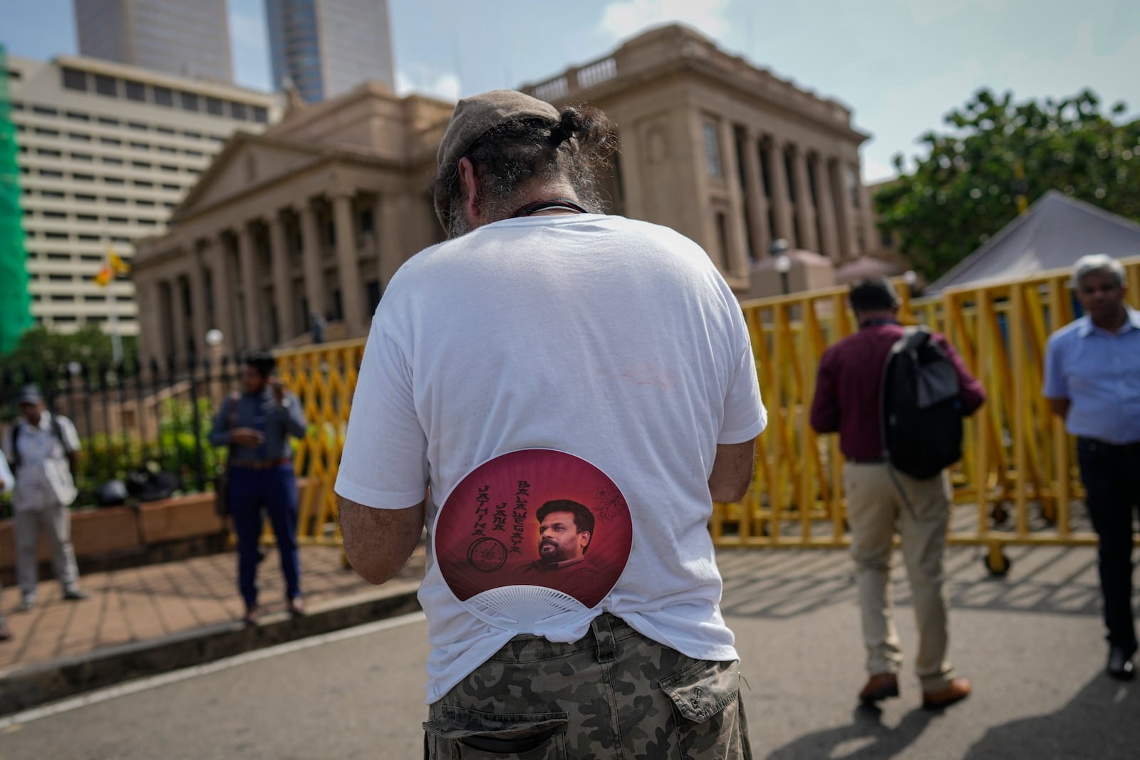 A supporter tucks a portrait of president elect Marxist lawmaker Anura Kumara Dissanayake on to his trousers as he waits for the swearing in ceremony outside president's office in Colombo, Sri Lanka, Monday, Sept. 23, 2024. (AP Photo/Eranga Jayawardena)