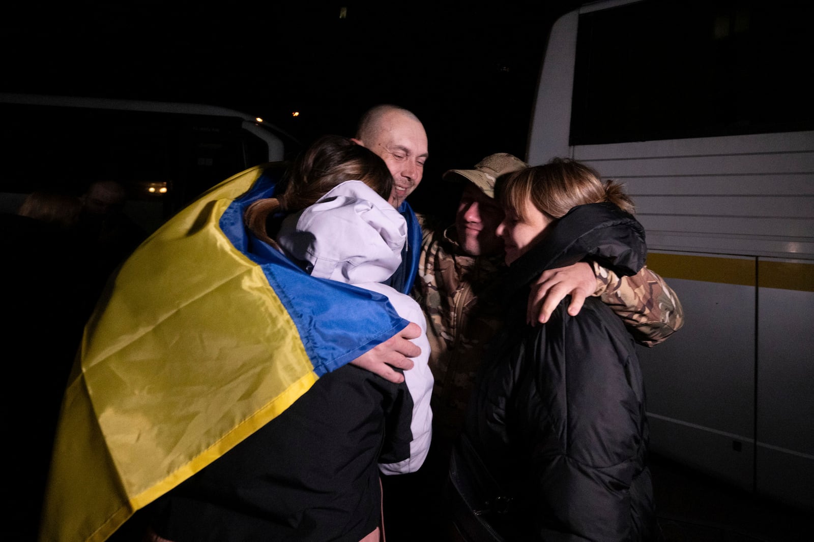 In this photo provided by the Press Service of the President of Ukraine on Oct. 19, 2024, a Ukrainian serviceman hugs his relatives after returning from captivity during a POWs exchange in an undisclosed location, Ukraine. (Press Service of the President of Ukraine via AP)