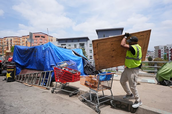 Jay Joshua cleans up around a homeless encampment where he currently lives, Monday, May 12, 2025, in Los Angeles. (AP Photo/Damian Dovarganes)