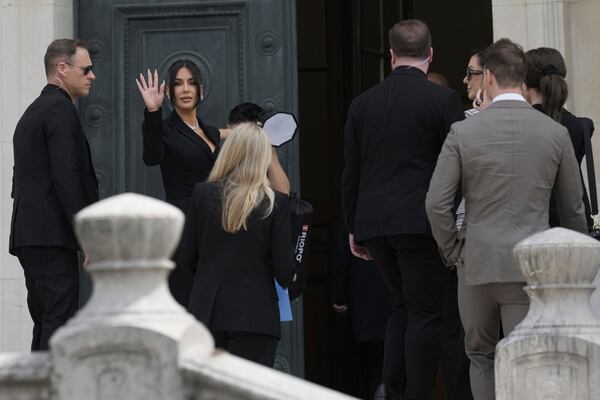 Kim Kardashian waves as she arrives to testify regarding a robbery of millions of dollars in jewels from her Paris hotel room in 2016, in Paris, Tuesday, May 13, 2025. (AP Photo/Aurelien Morissard)