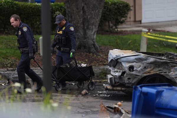 Police help rescue dogs from a home after a small plane crashed into a San Diego neighborhood earlier, setting several homes on fire and forcing evacuations along several blocks, Thursday, May 22, 2025. (AP Photo/Gregory Bull)