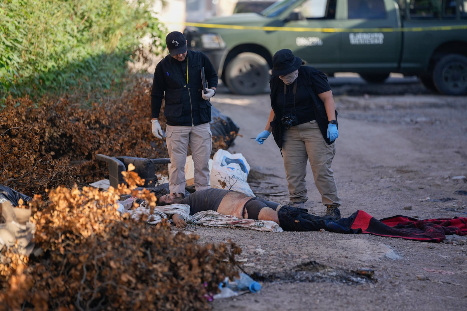 Crime scene investigators work at the site where a body was found lying on a street in La Costerita neighborhood of Culiacan, Sinaloa state, Mexico, Thursday, Sept. 19, 2024. (AP Photo/Eduardo Verdugo)