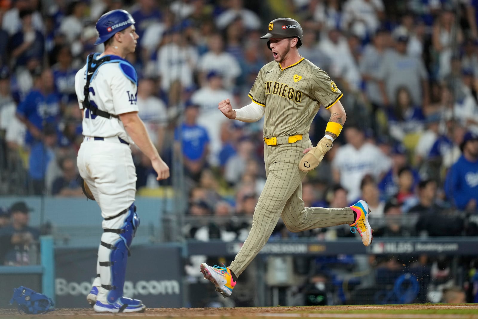 San Diego Padres' Jackson Merrill, right, celebrates as he scores as Los Angeles Dodgers catcher Will Smith, left, reacts during the third inning in Game 1 of baseball's NL Division Series, Saturday, Oct. 5, 2024, in Los Angeles. (AP Photo/Mark J. Terrill)