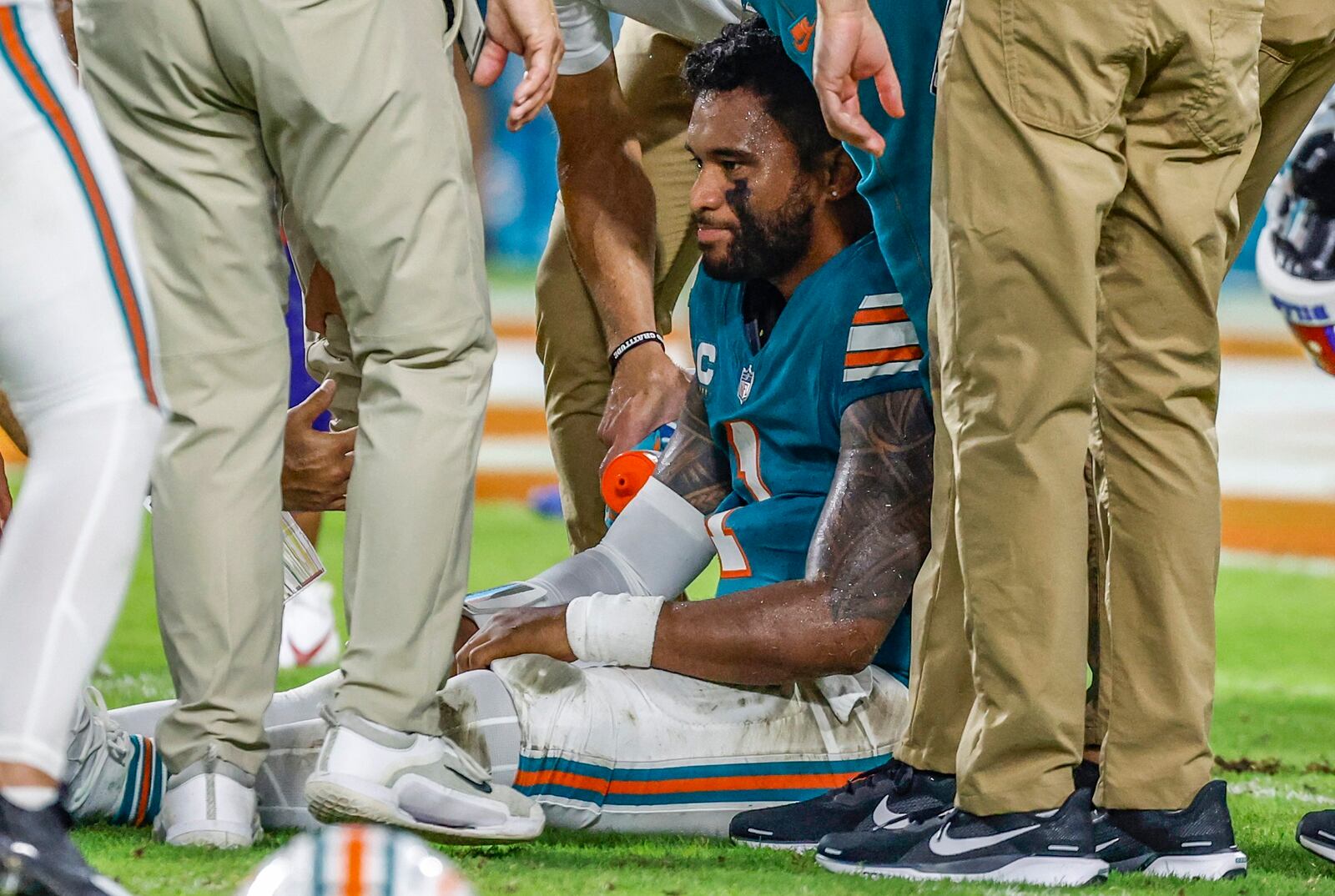 Miami Dolphins quarterback Tua Tagovailoa (1) sits on the field as he is attended to after an injury during the game against the Buffalo Bills in the second half of an NFL football game on Thursday, Sept. 12, 2024. (Al Diaz/Miami Herald via AP)