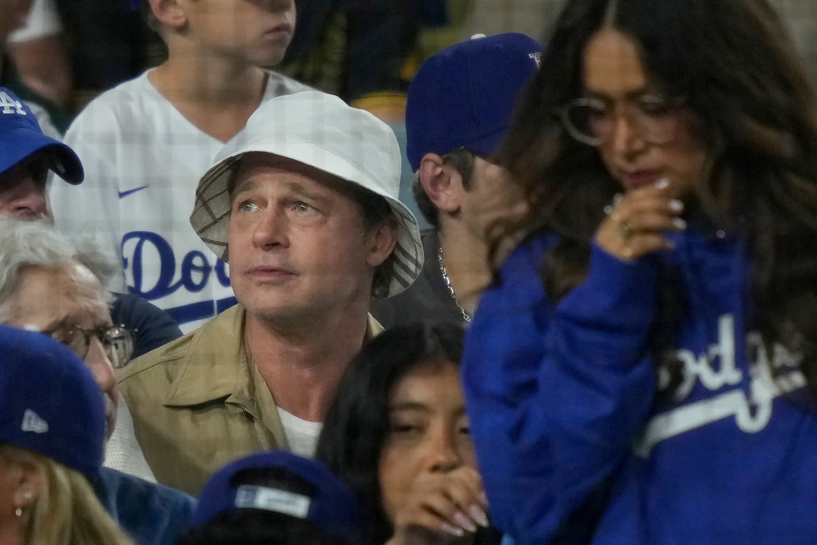 Brad Pitt, in white hat, watches from the stands during Game 1 of baseball's NL Division Series between the Los Angeles Dodgers and the San Diego Padres, Saturday, Oct. 5, 2024, in Los Angeles. (AP Photo/Mark J. Terrill)