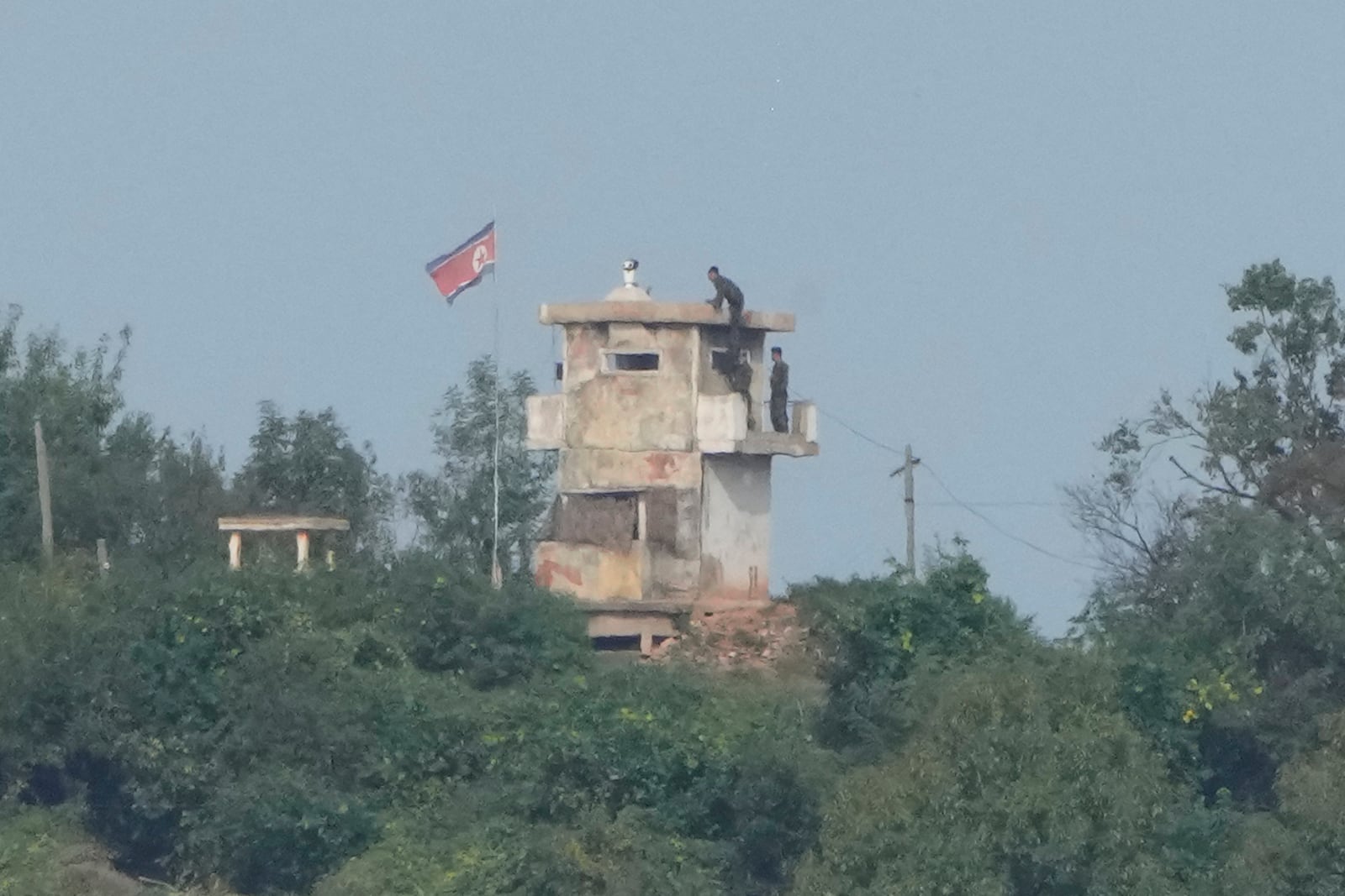 North Korean soldiers work at the North's military guard post as a North Korean flag flutters in the wind, are seen from Paju, South Korea, near the border with North Korea, Thursday, Oct. 10, 2024. (AP Photo/Ahn Young-joon)